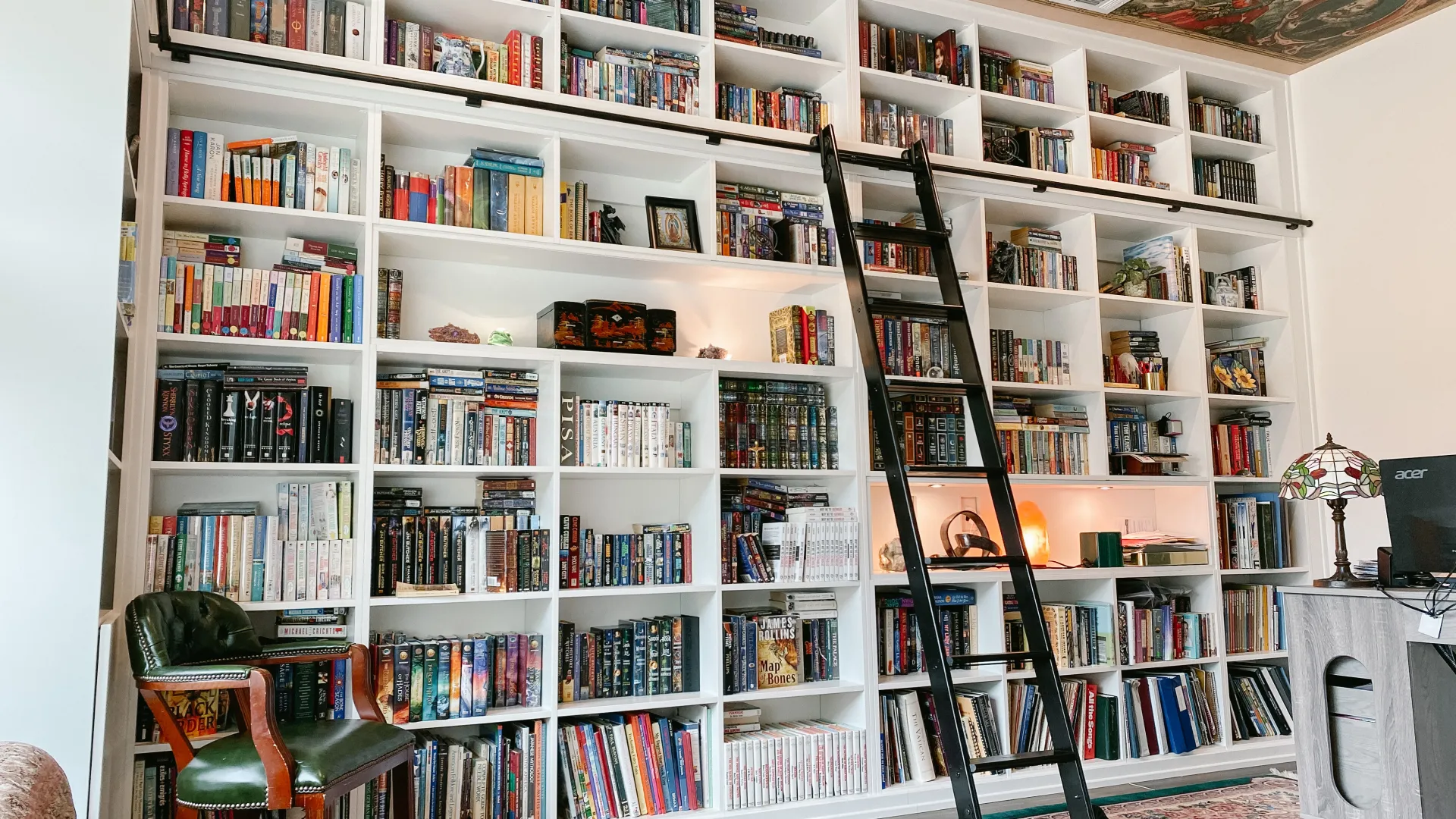 a room with shelves of books with a black ladder