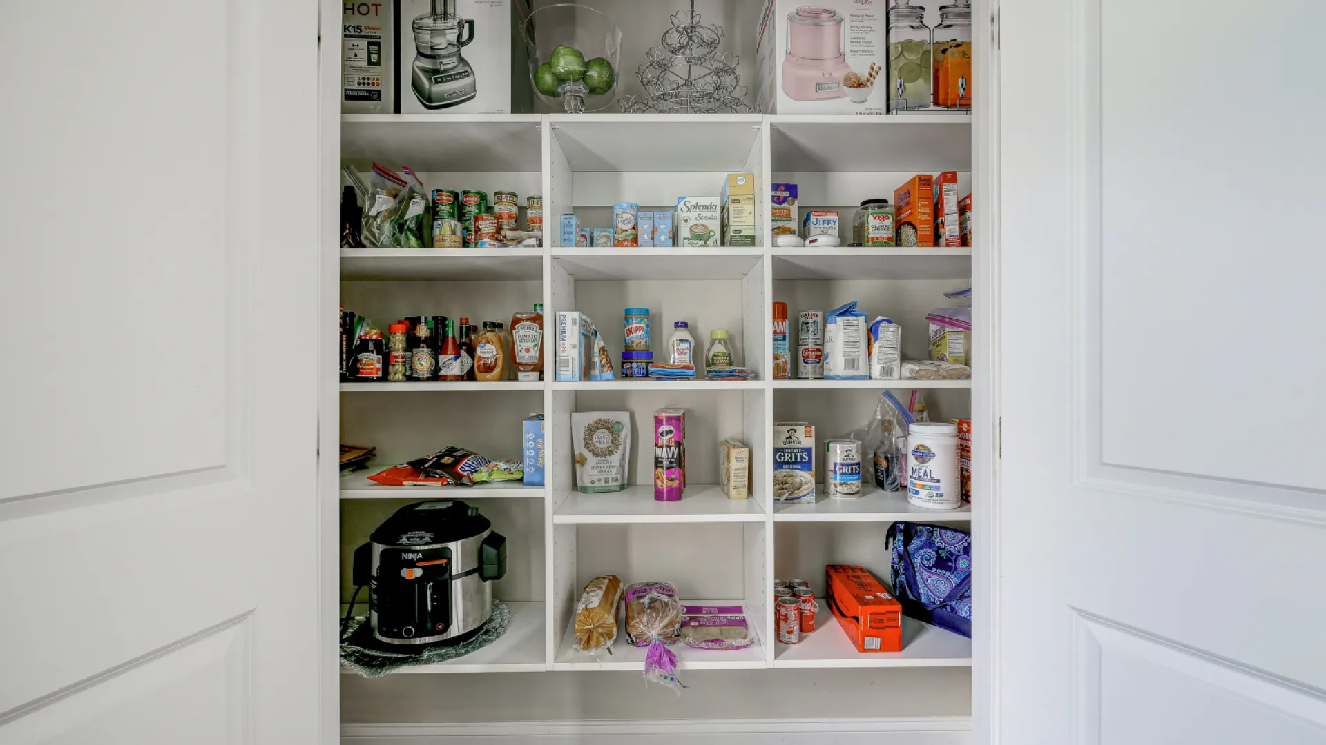 white painted pantry filled with food items and kitchen appliances