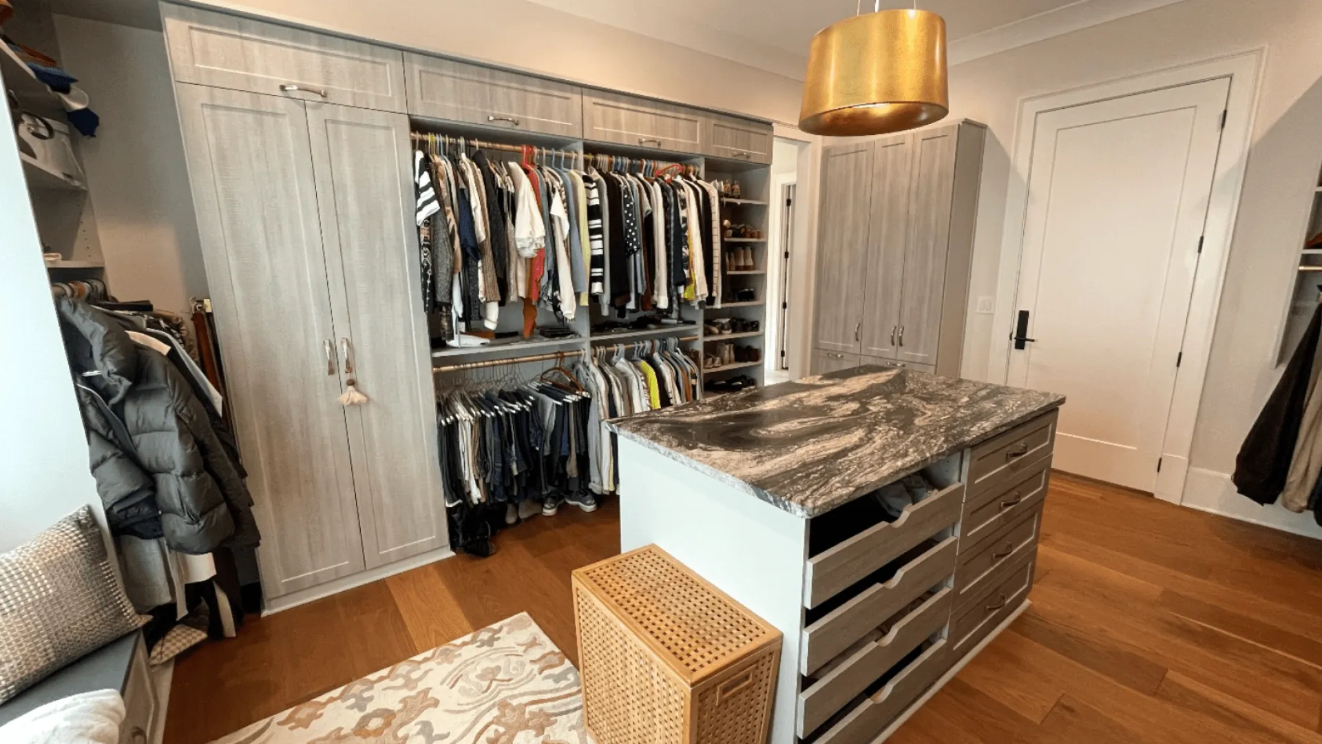 Install custom closet. Minroom with a shelf and a table with clothes on it