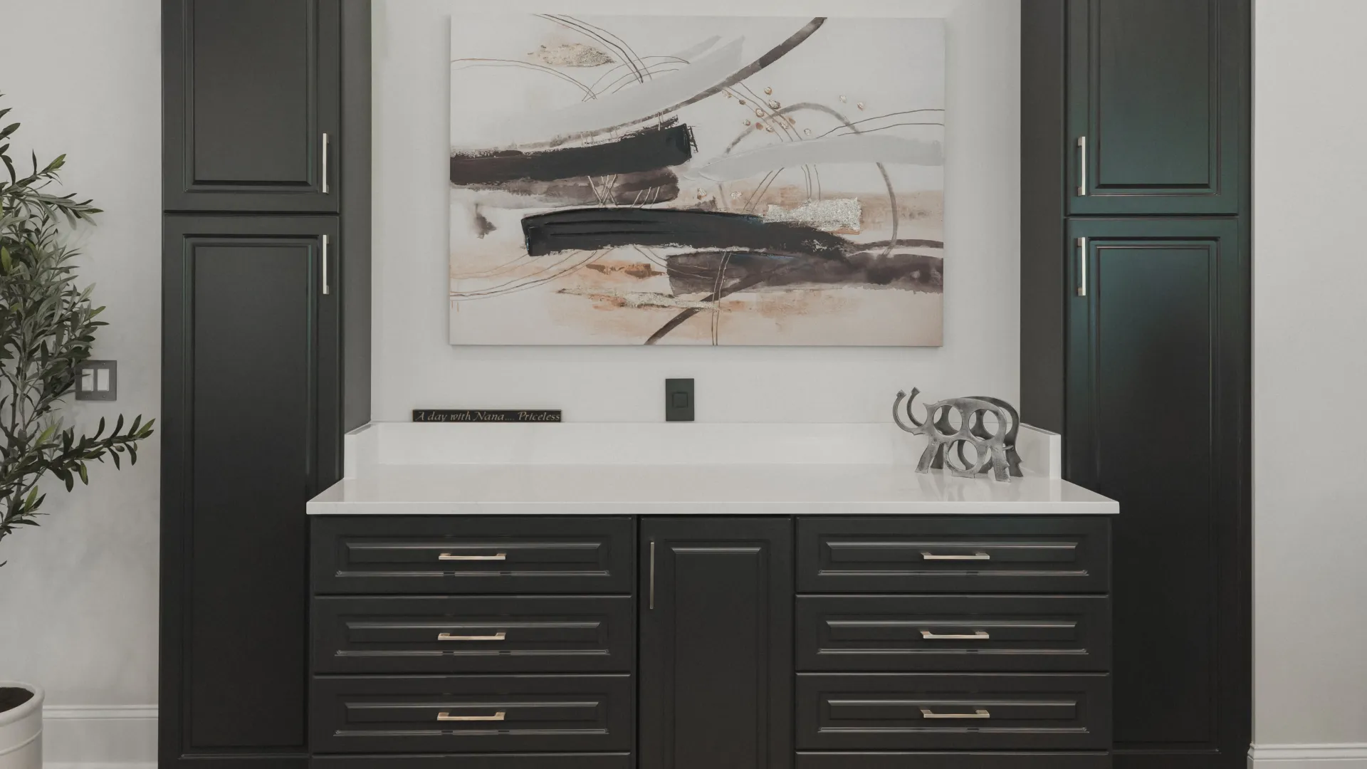Custom designed home bar with black cabinets and drawers with a white countertop and abstract wall art