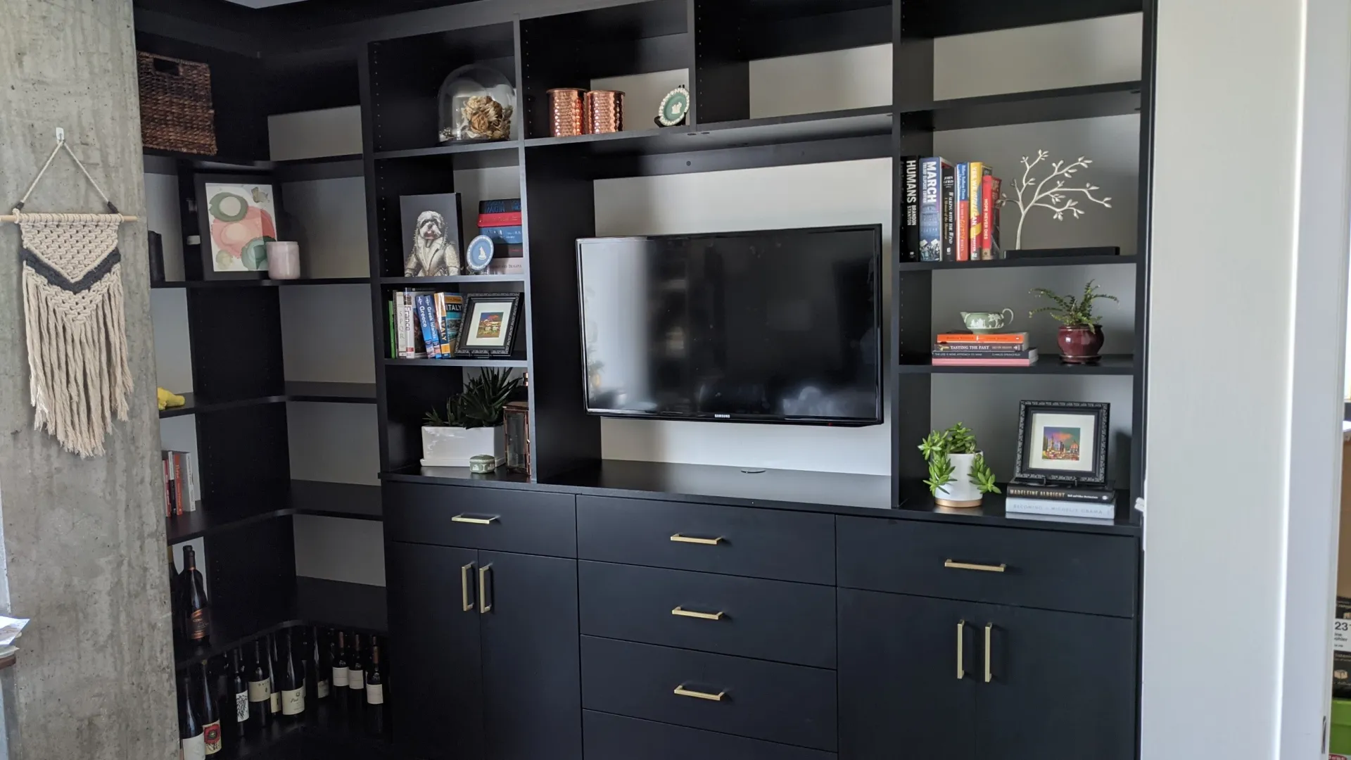 a black cabinet with a tv and shelves with objects on it