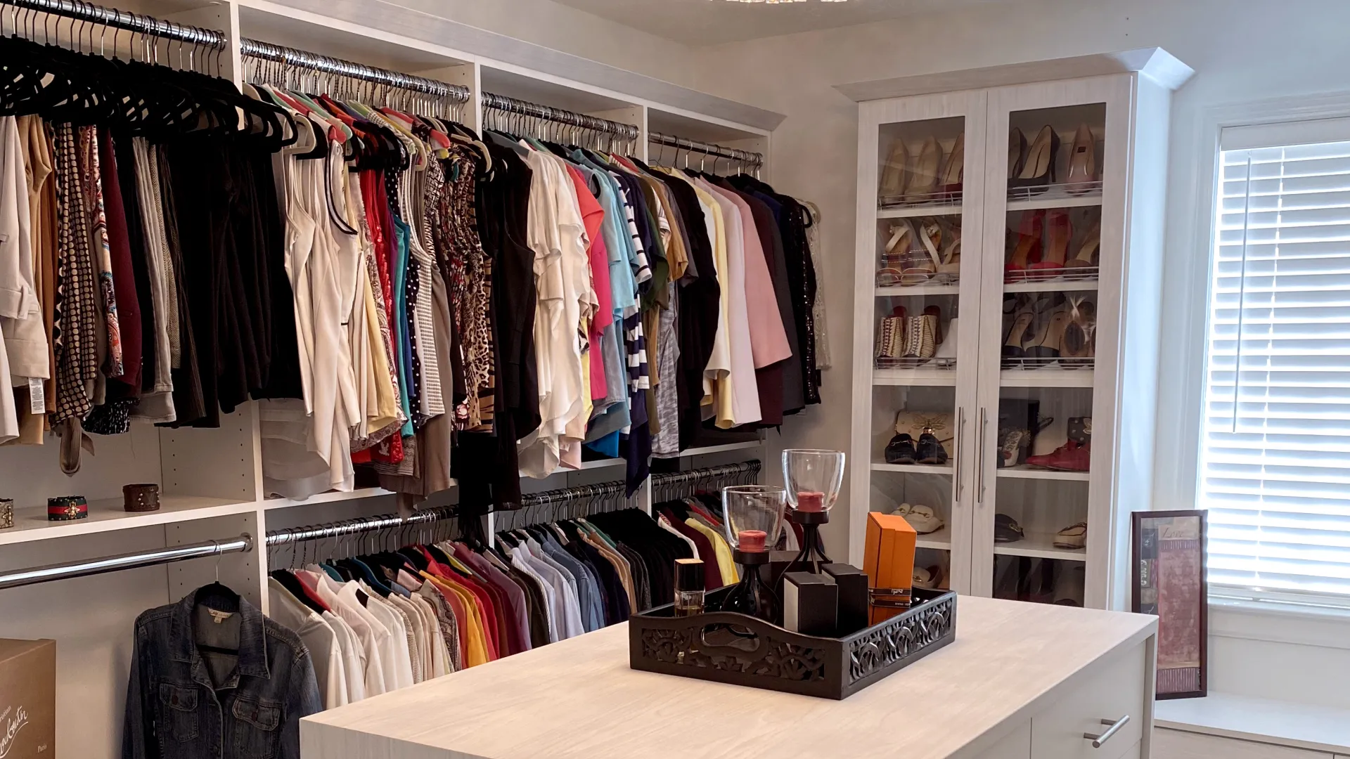 a room with a white cabinet and a white counter with a white shelf with clothes on it