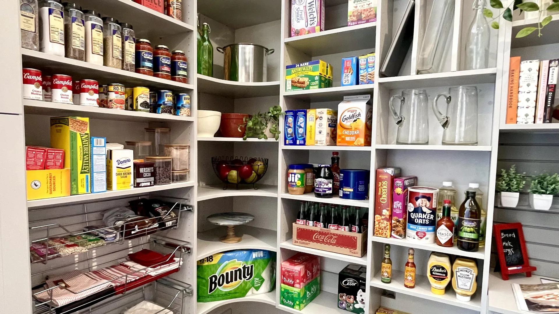 Organized kitchen pantry shelves stocked with canned goods, snacks, beverages, Bounty paper towels and glass pitchers