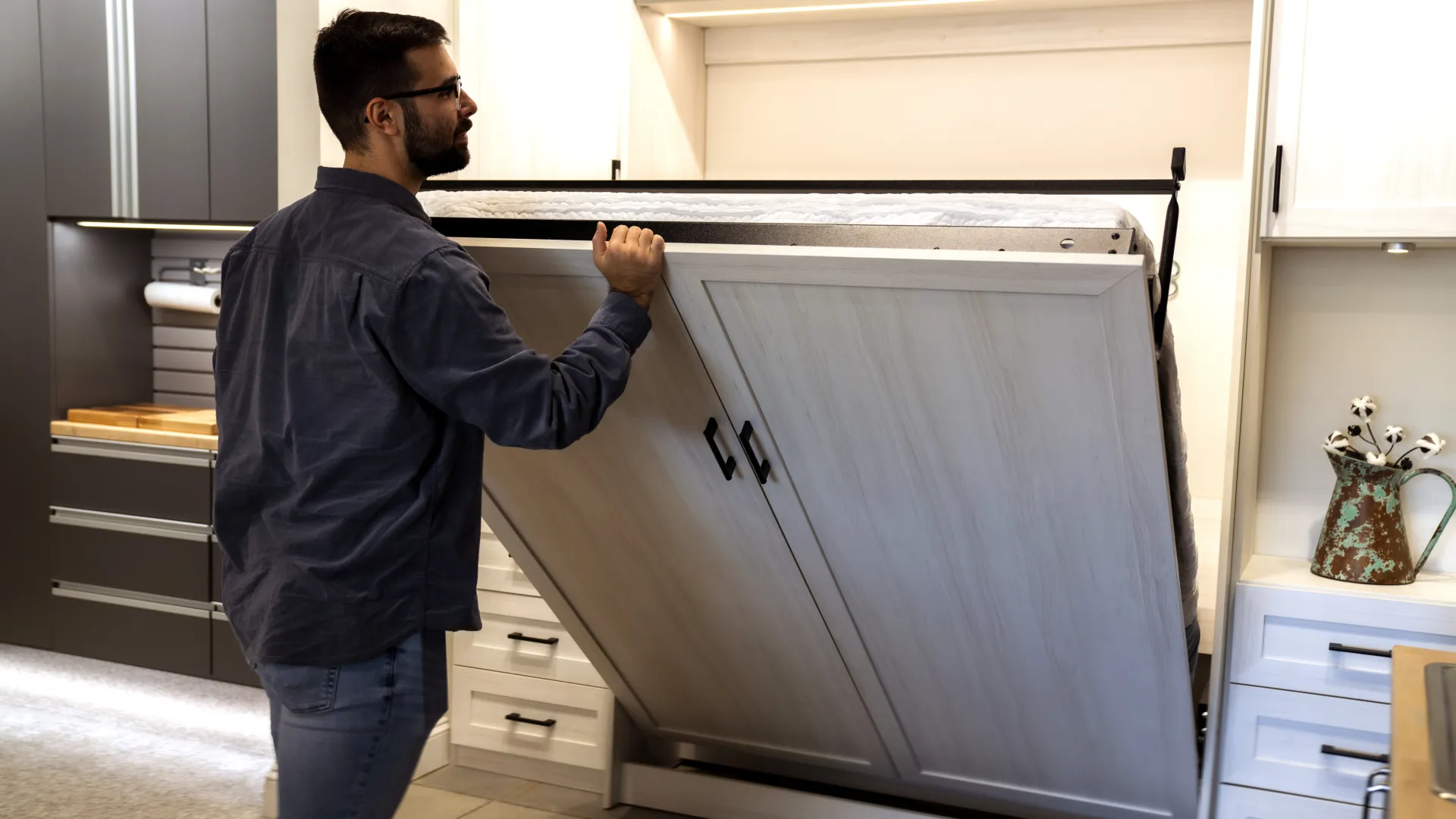 a man pulling down a wall bed murphy bed