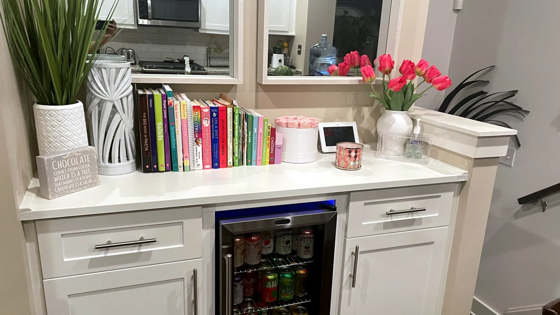 a white counter with a vase of flowers and other objects on it