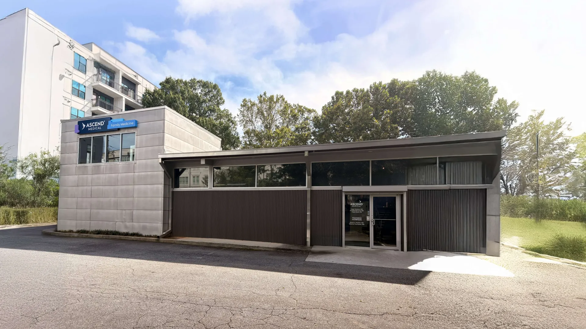 Modern commercial building with Ascend Mental Health signage under clear sky and surrounded by trees.