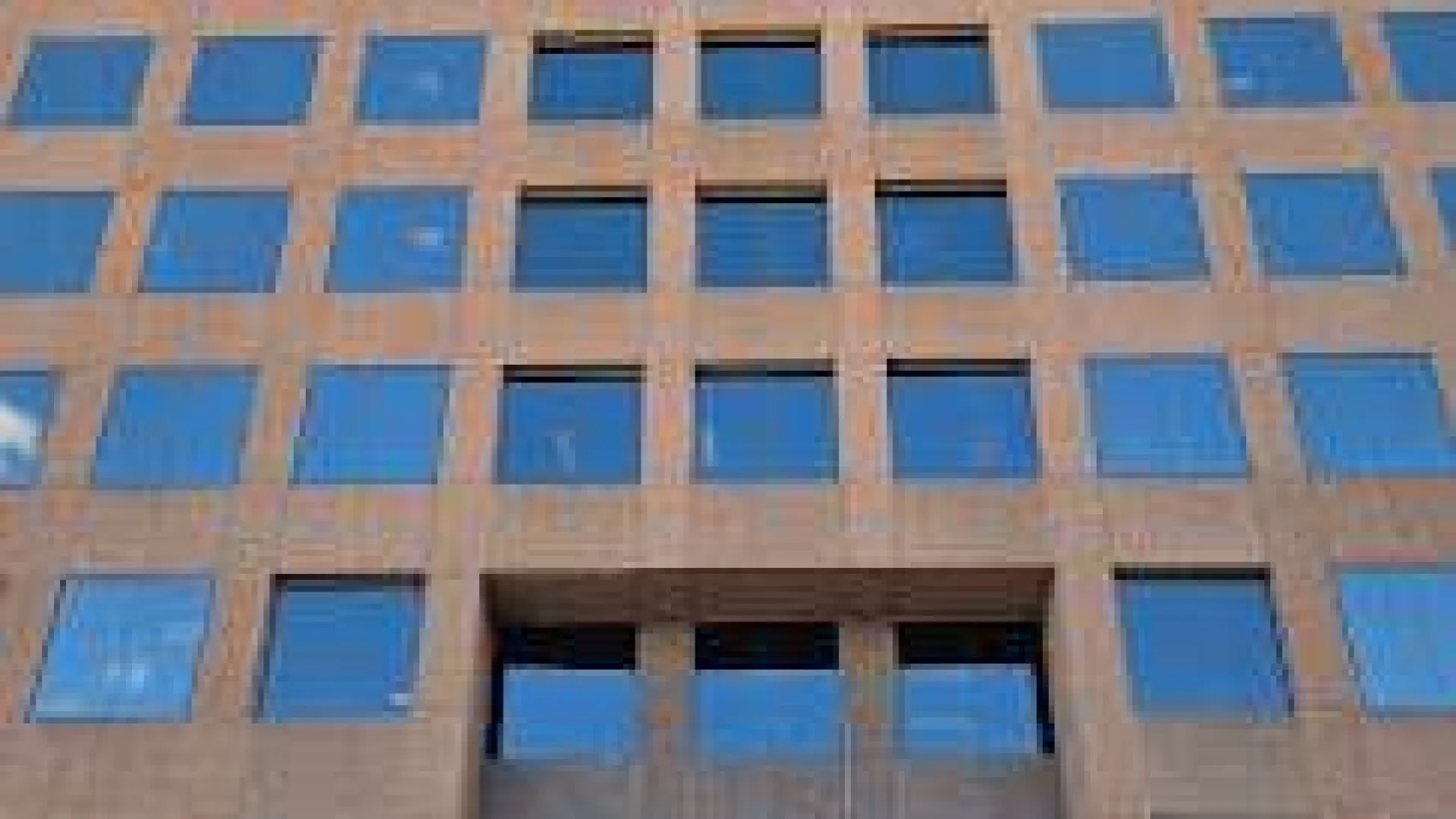 Tall office building with reflective glass windows and a clear blue sky above.