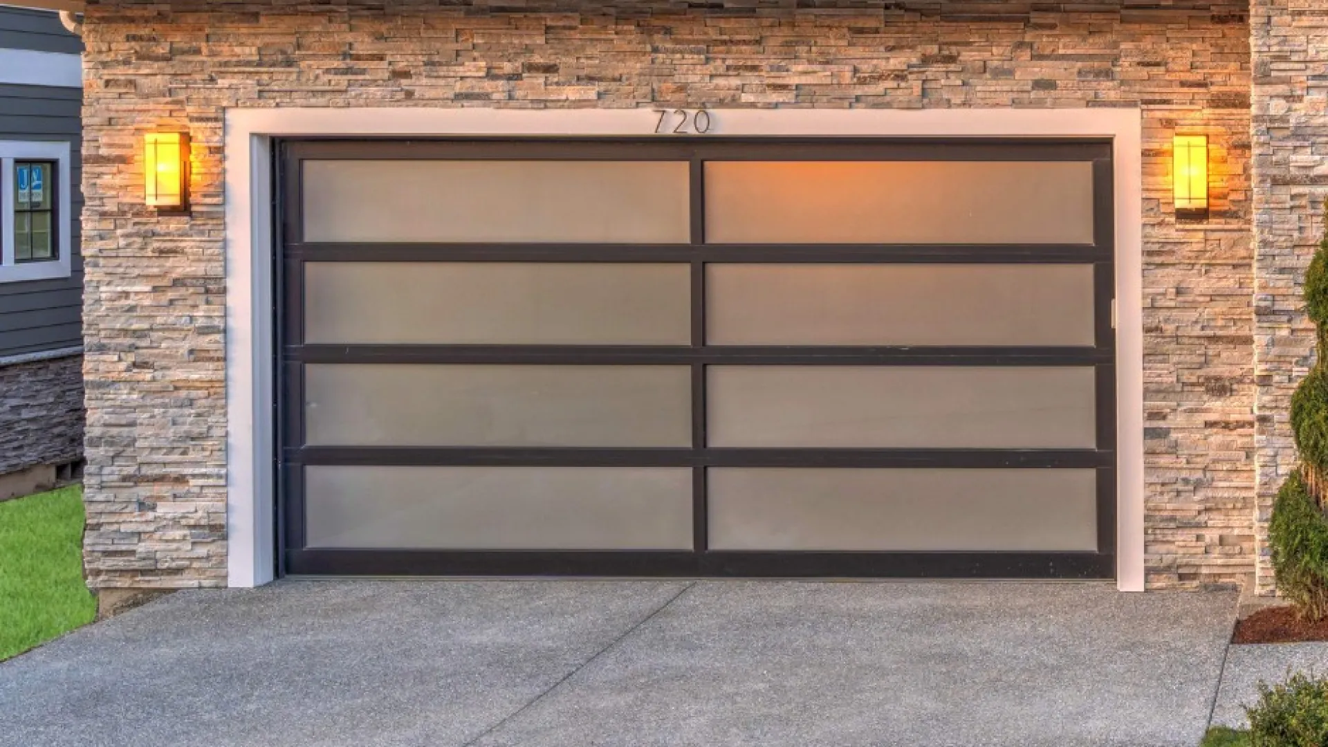 Modern garage door with frosted glass panels and stone facade accents in a contemporary home setting.