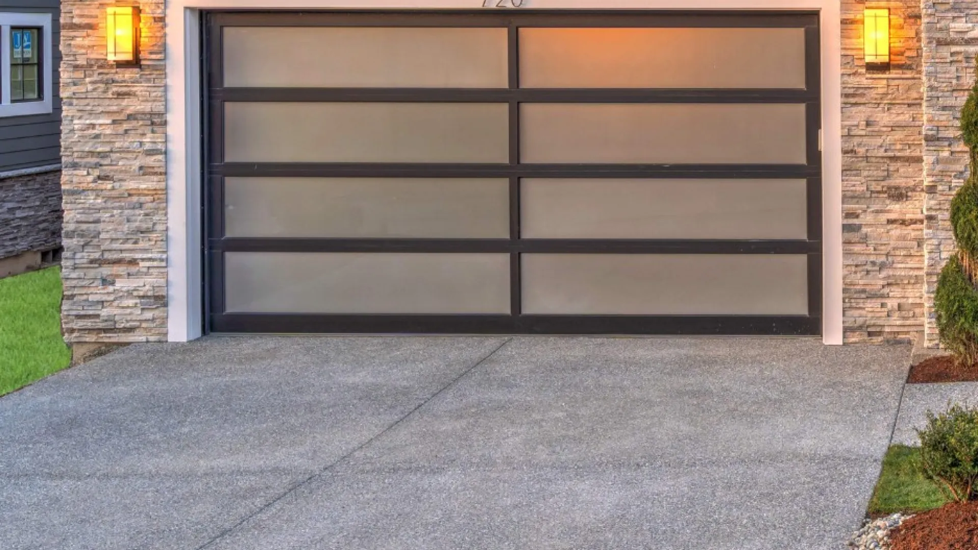 Modern garage door with frosted glass panels and stone facade accents in a contemporary home setting.