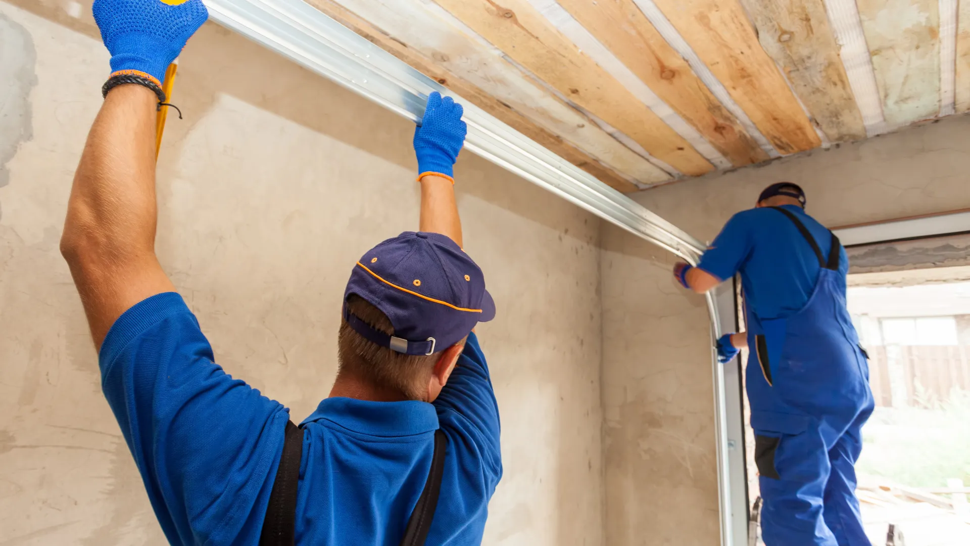 Two workers installing ceiling beams in a home renovation project, showcasing teamwork and construction skills.