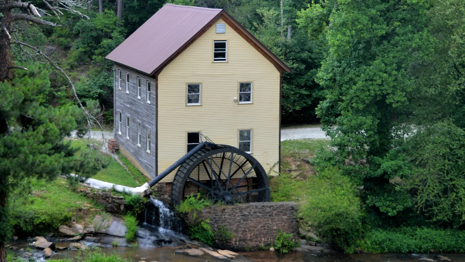 a house with a bridge over a stream in a forest