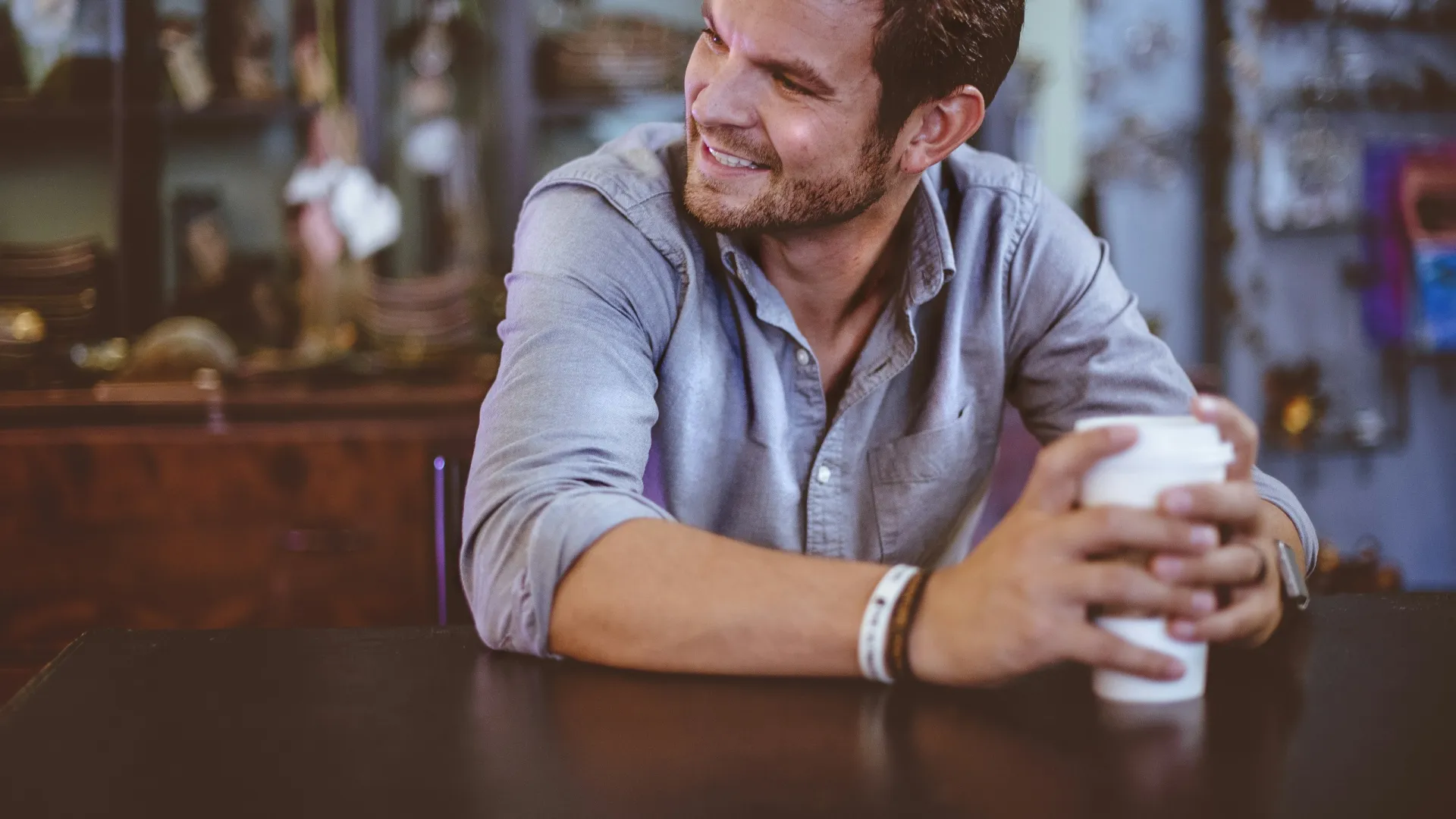 a man sitting at a table and holding a cup