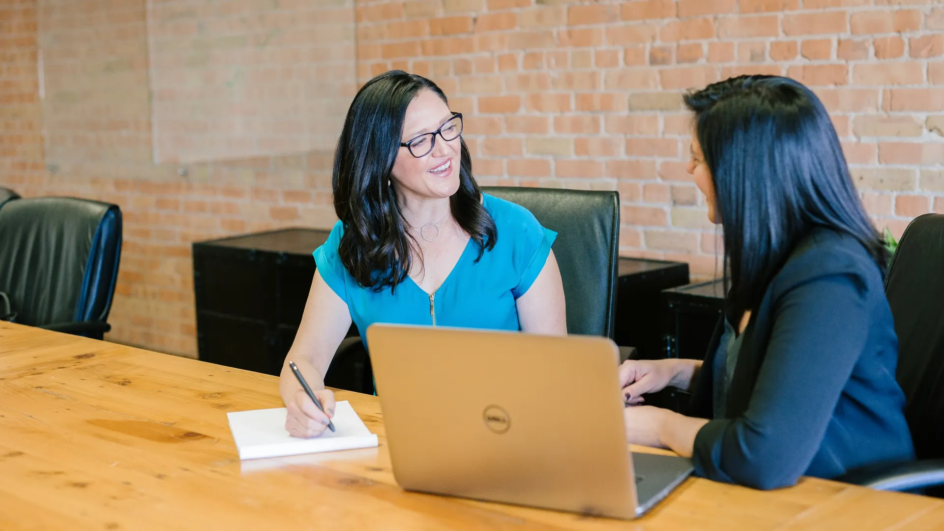 a couple of women sitting at a table looking at a laptop