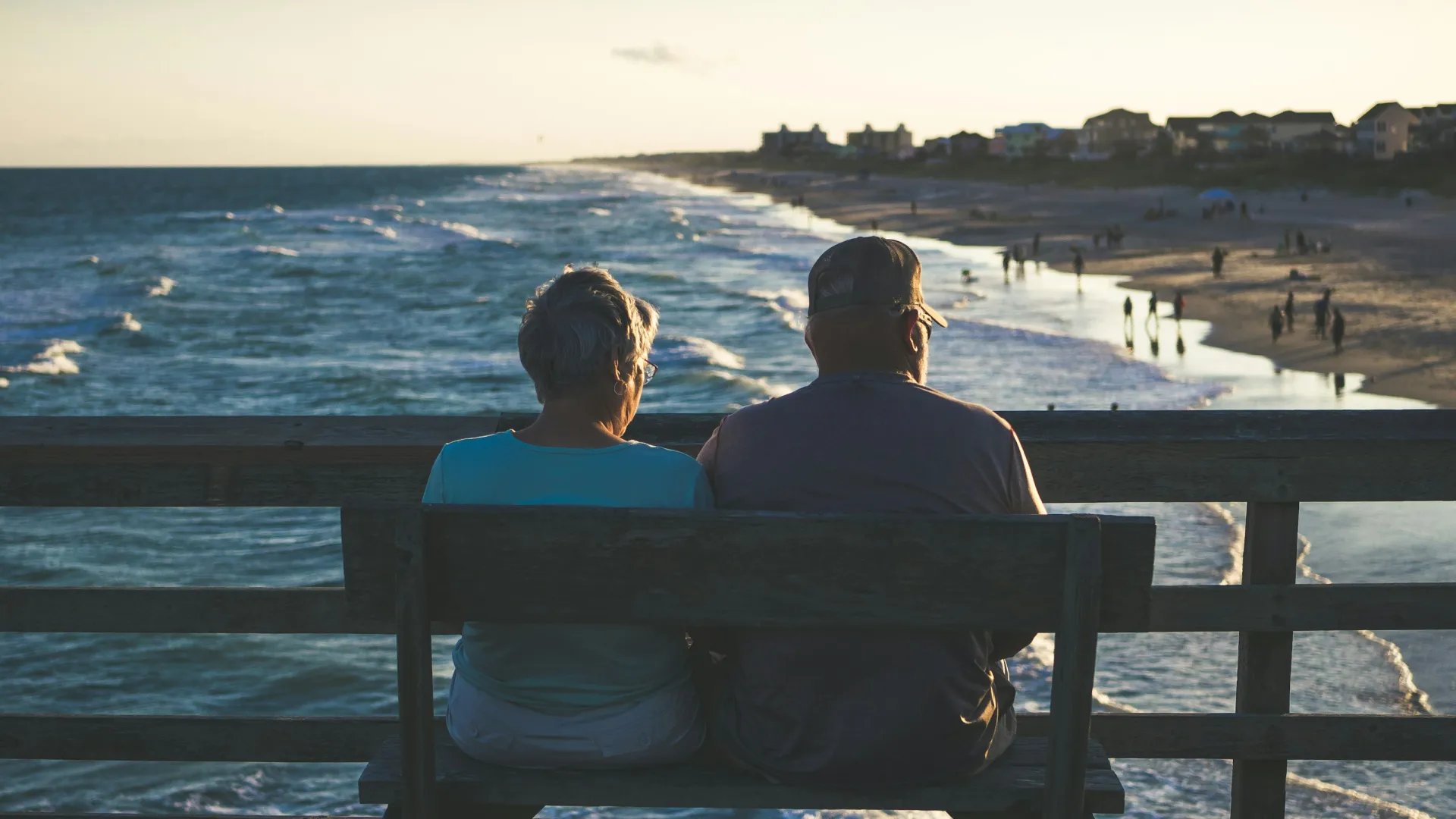 a couple sitting on a bench looking at the water