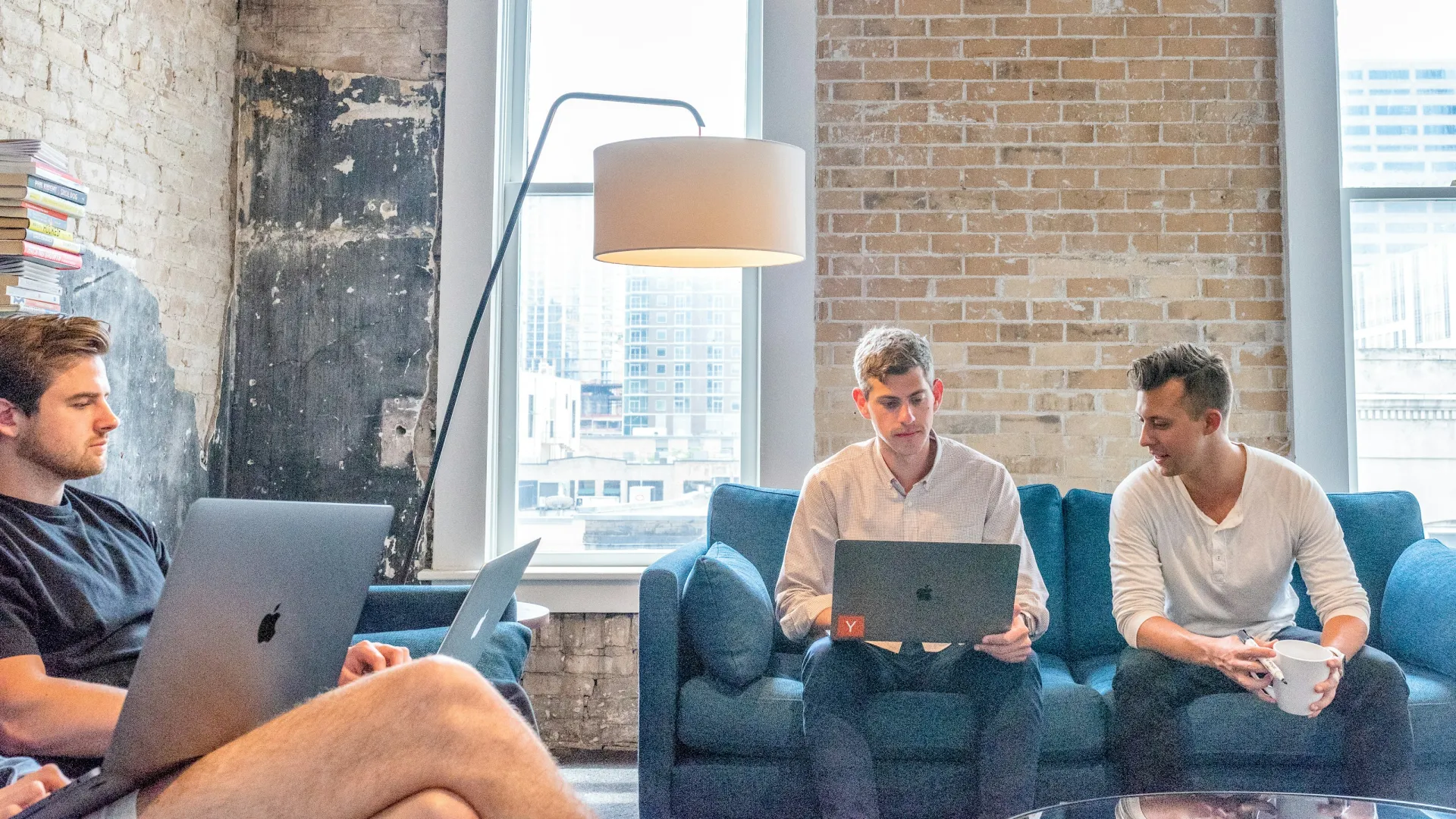 men sitting on a couch using laptops