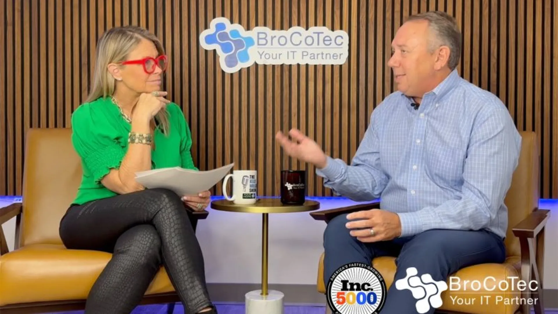 Two professionals engaged in a discussion in an office setting with BroCoTec branding behind them.