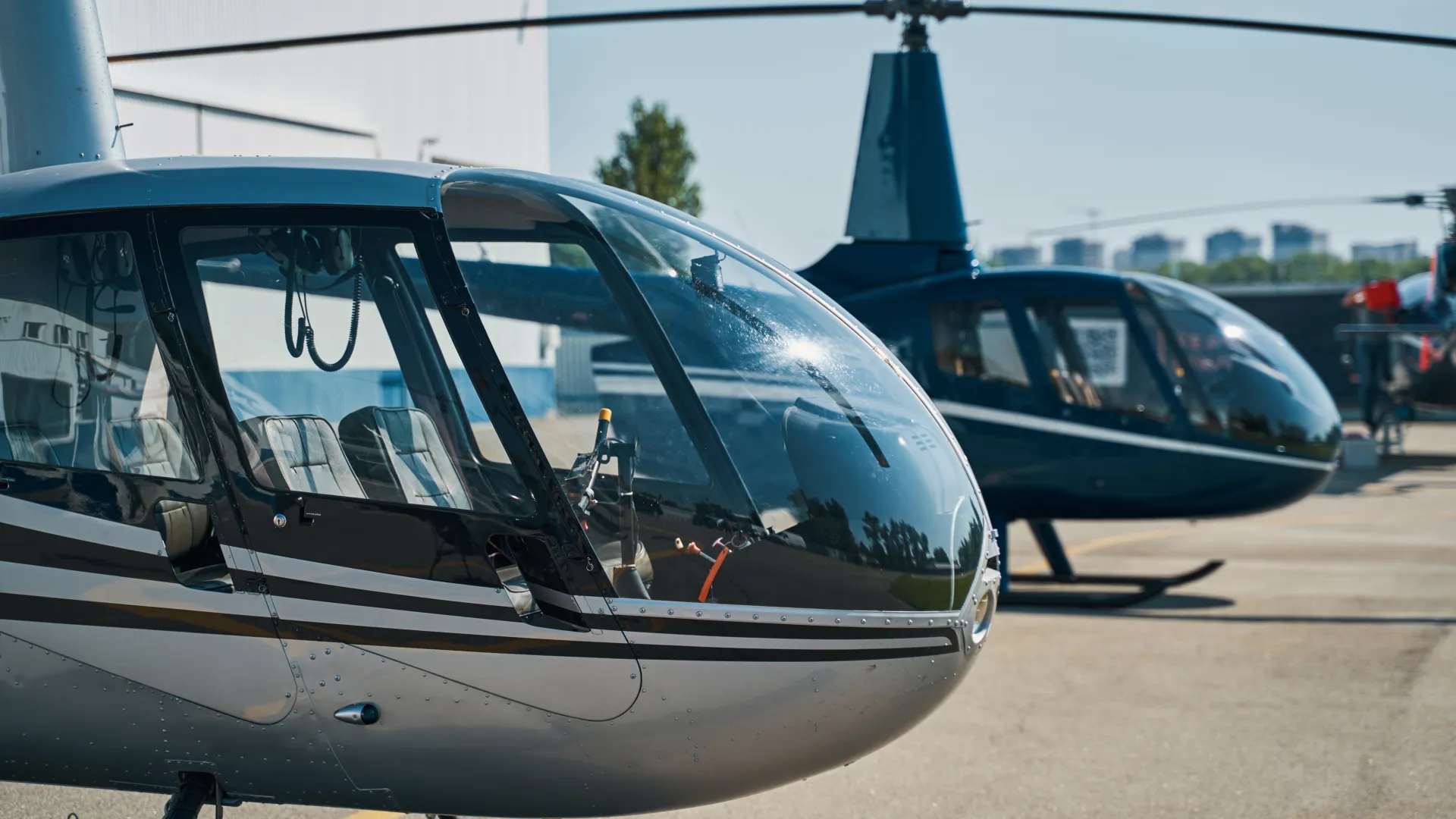 Close-up of two parked helicopters on a sunny day at an airport with clear blue sky background