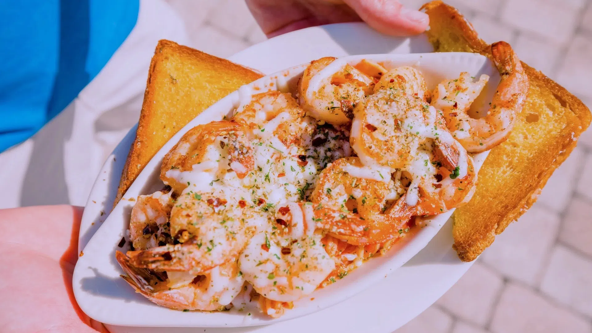 Plate of seasoned shrimp with creamy sauce served with two slices of toasted bread on a white dish.