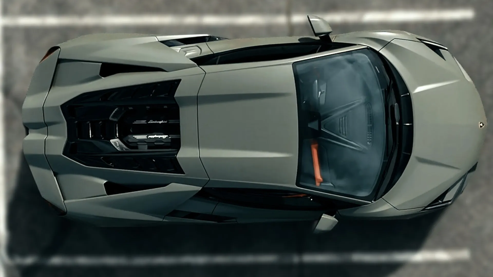 Top view of a sleek silver Lamborghini sports car parked in a marked parking space on asphalt.