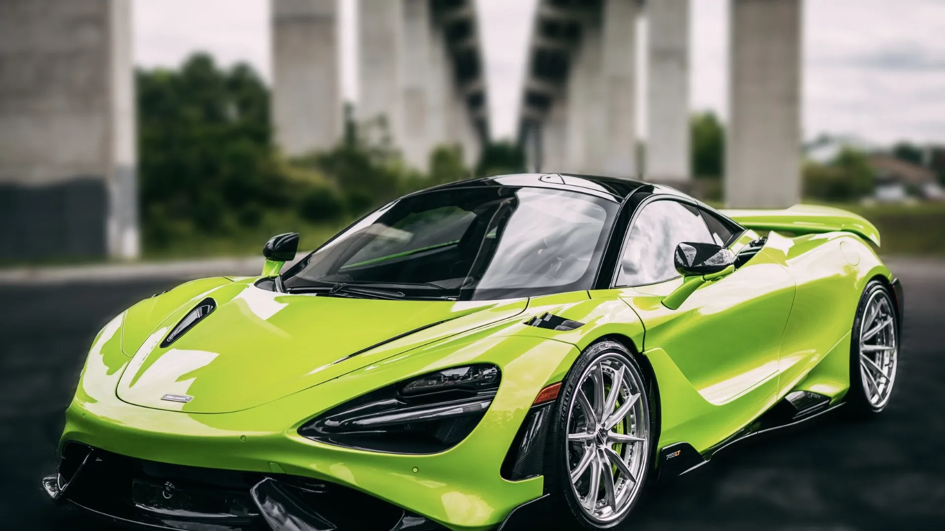 Bright green McLaren sports car parked under a concrete bridge with sleek aerodynamic design.