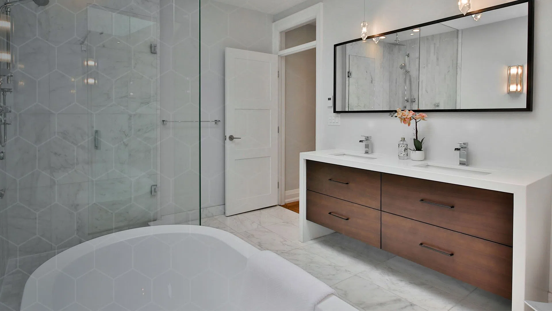 Modern bathroom with a white freestanding tub, glass shower enclosure, double sink vanity, and large mirror.