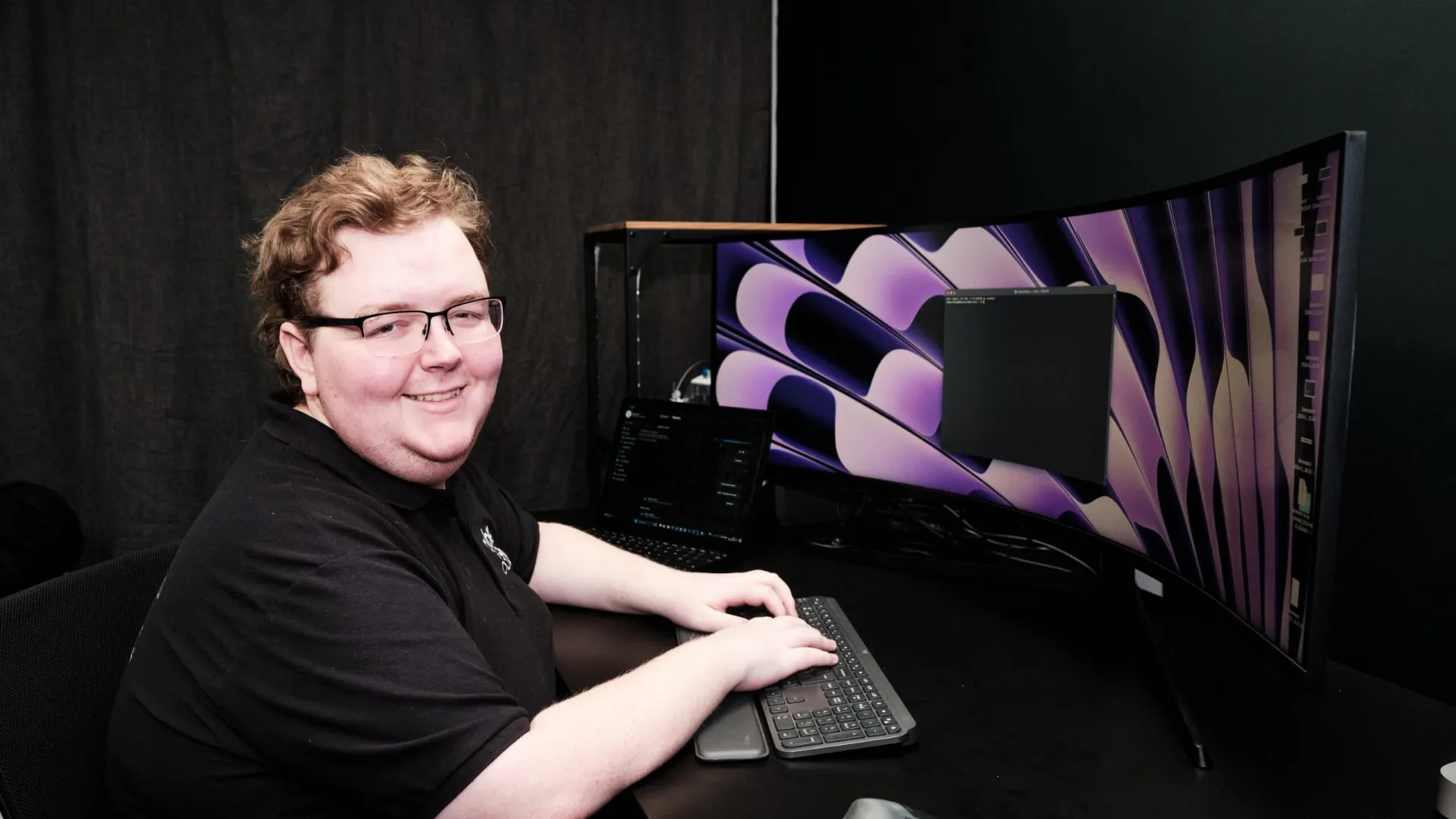 a person sitting at a desk with a computer and a keyboard