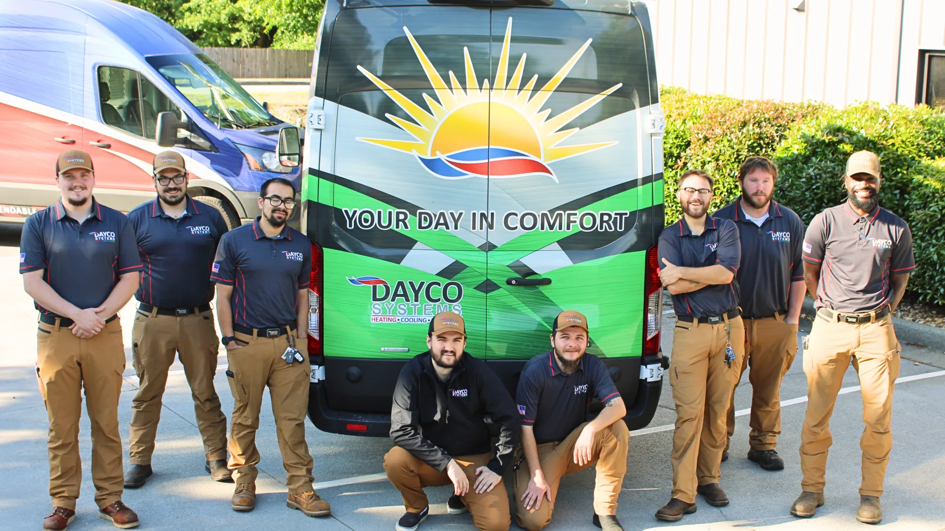 Dayco Systems HVAC team posing in front of branded service vans with comfort-themed logo and slogan