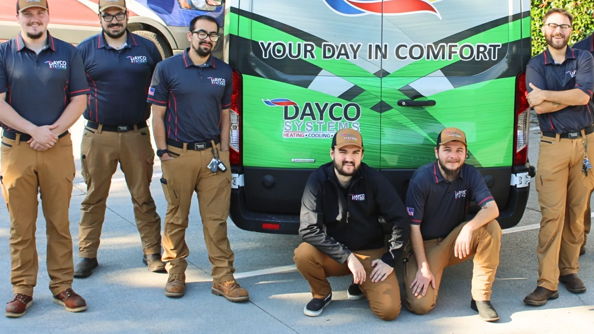 Dayco Systems HVAC team posing in front of branded service vans with comfort-themed logo and slogan