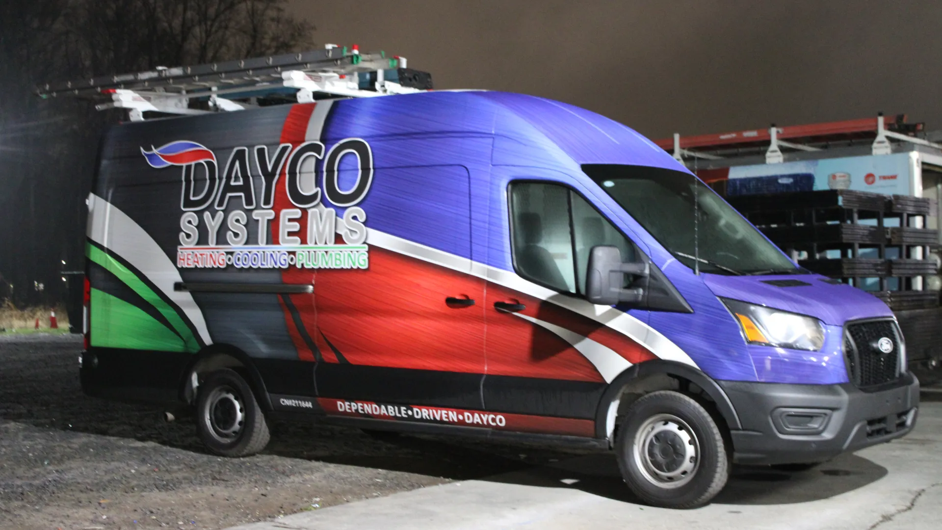 Dayco Systems service van with colorful heating, cooling, and plumbing design parked at night.