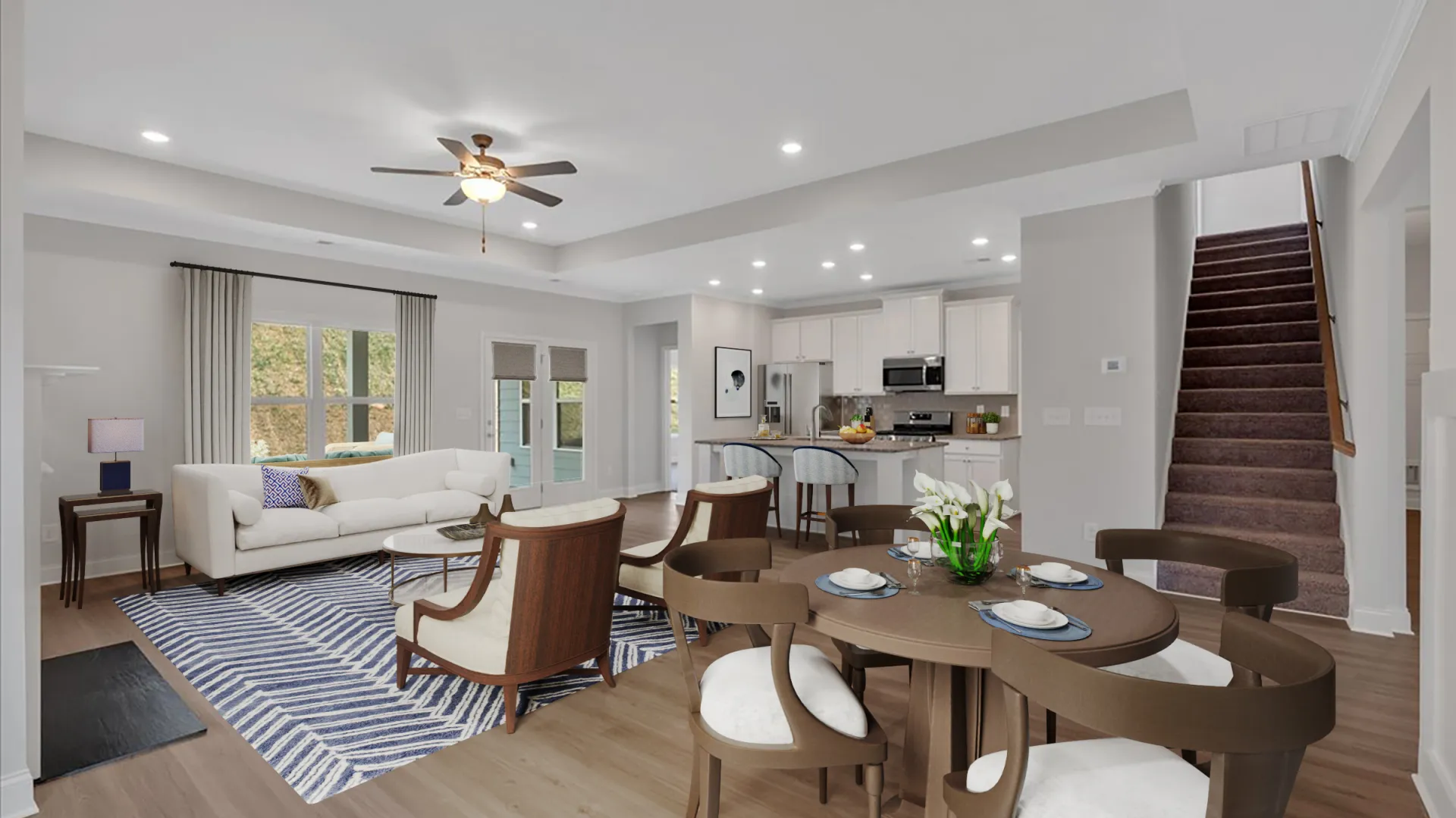 Bright modern open-concept living room with tufted sofa, brown chair, round coffee table, and kitchen in background