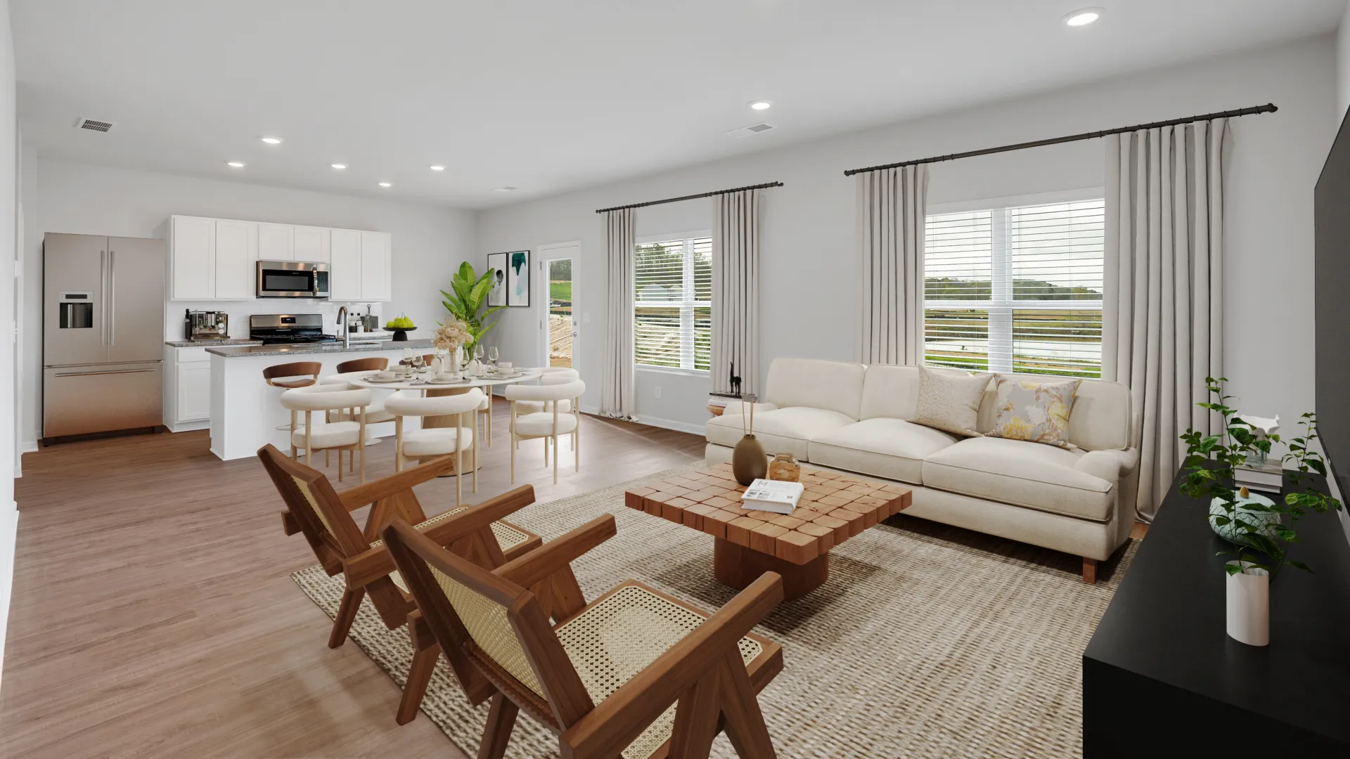 Bright open living room and kitchen with modern furniture, wood floors, and large windows with drapes.
