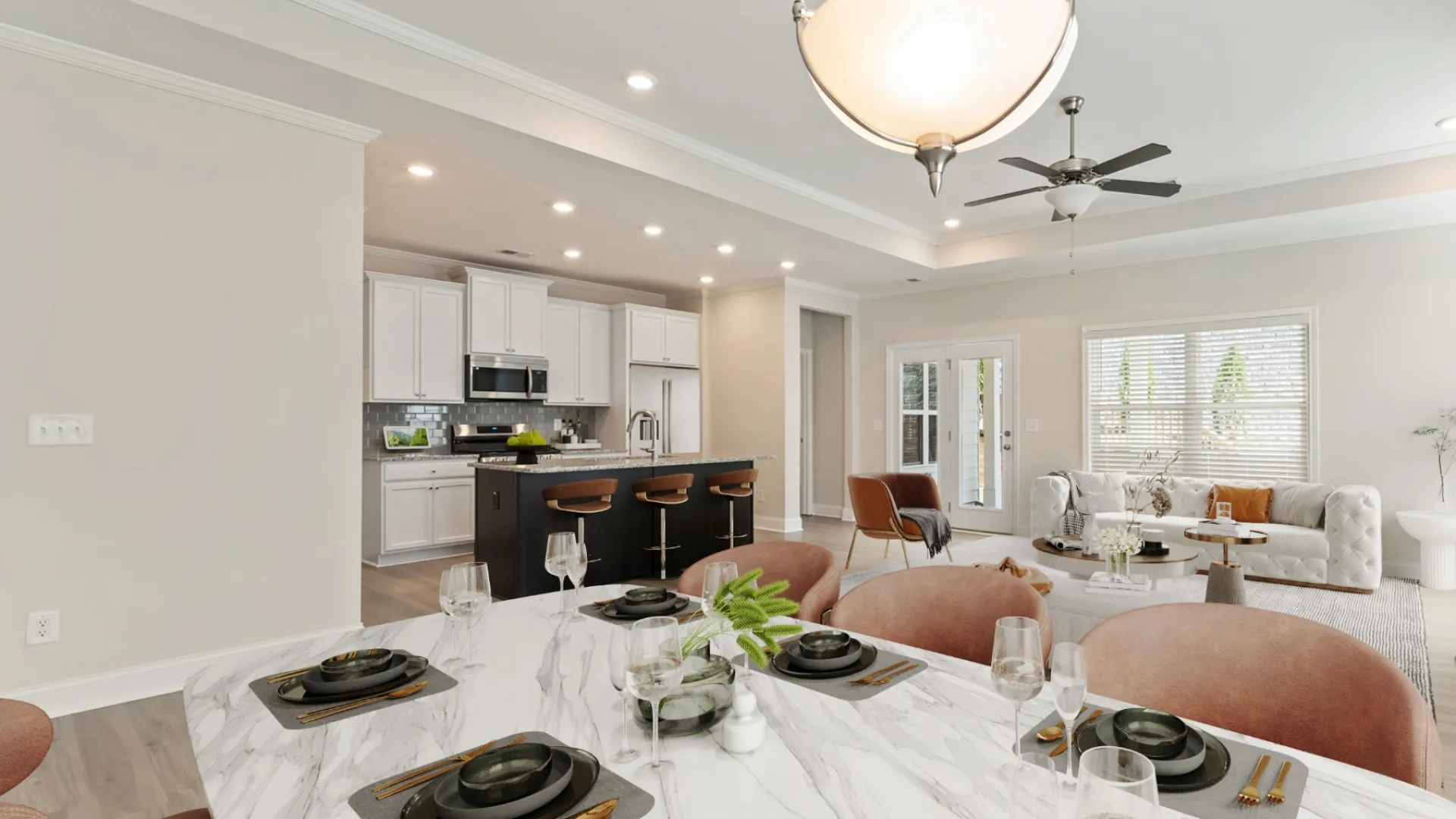 Modern open-concept dining and living room with marble table, pink chairs, white kitchen, and cozy seating area.