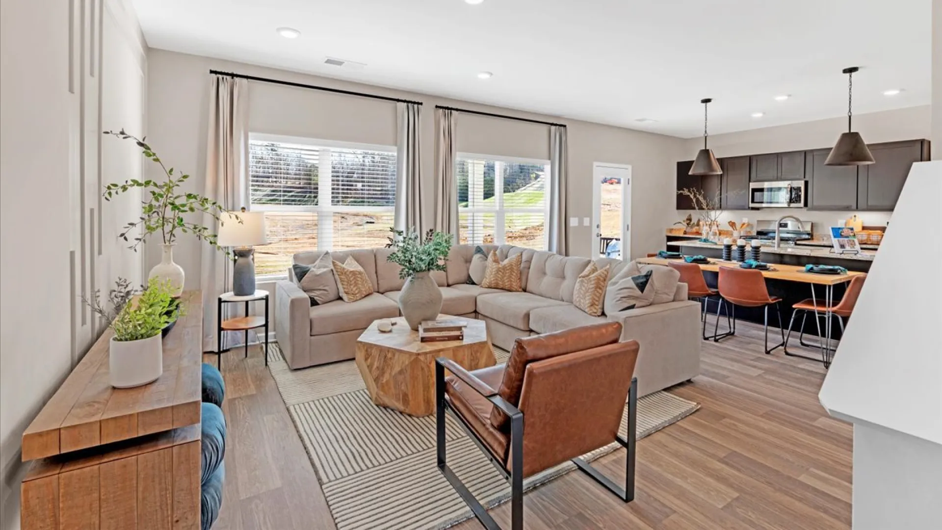 Modern living room with cozy furniture, large windows, and warm wood accents.