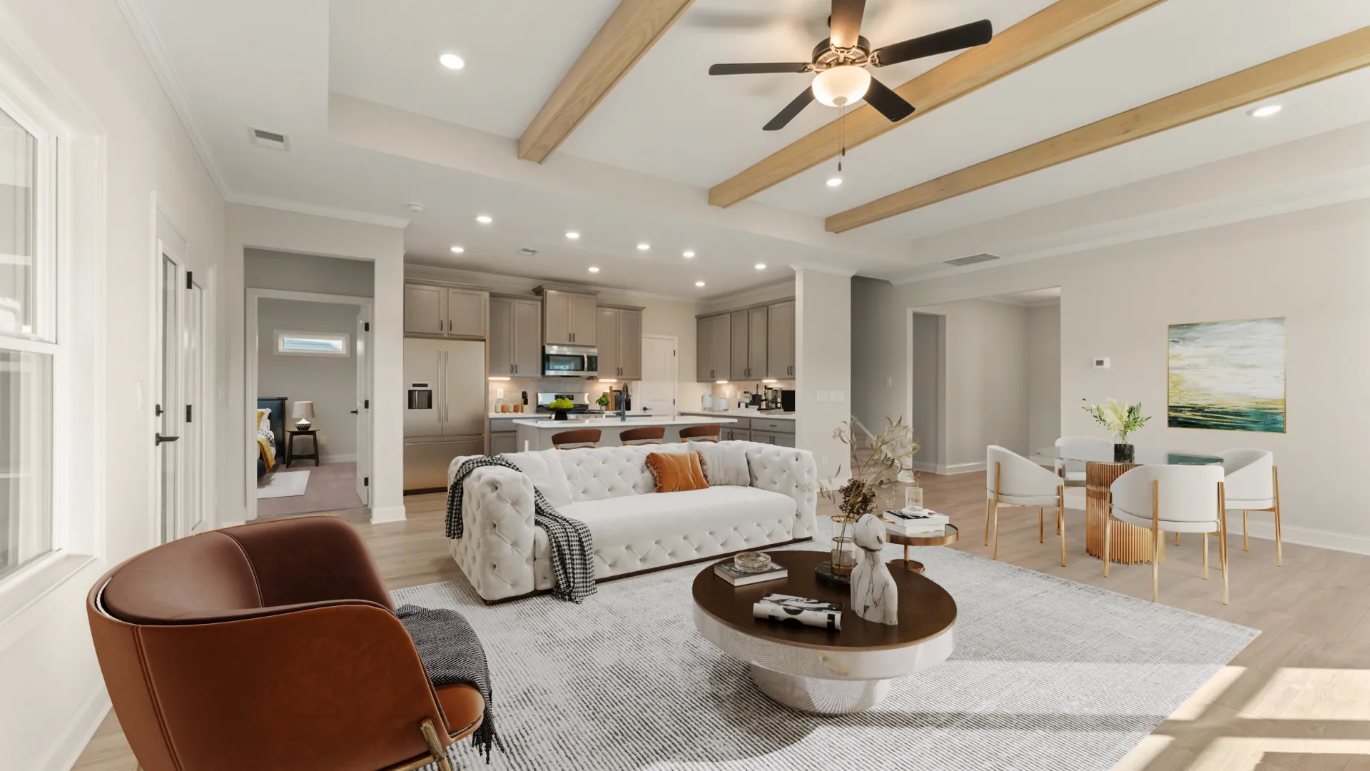Bright modern open-concept living room with tufted sofa, brown chair, round coffee table, and kitchen in background