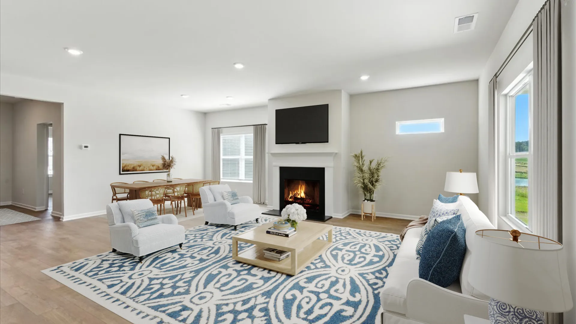 Modern open-concept dining and living room with marble table, pink chairs, white kitchen, and cozy seating area.