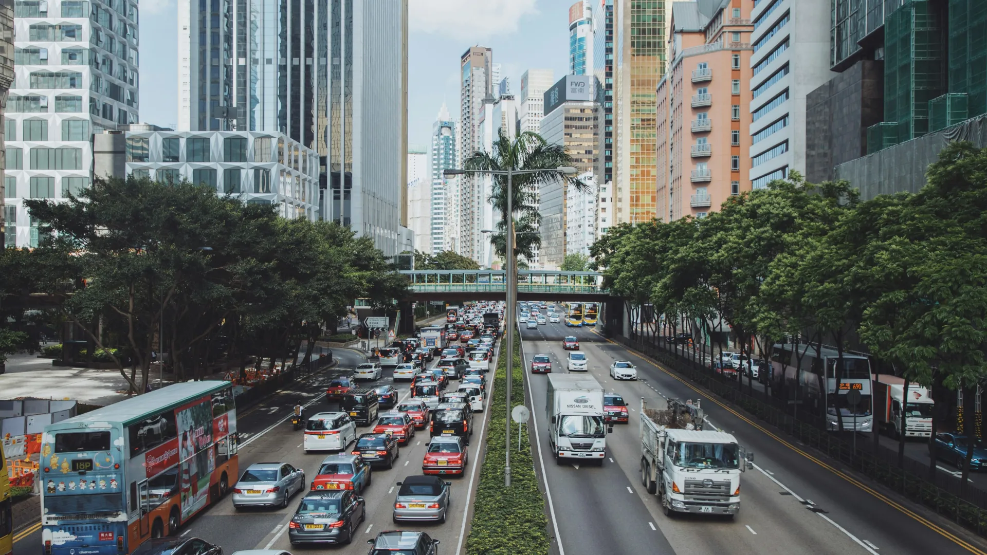 Busy multi-lane city street with heavy traffic and tall modern buildings on a cloudy day.