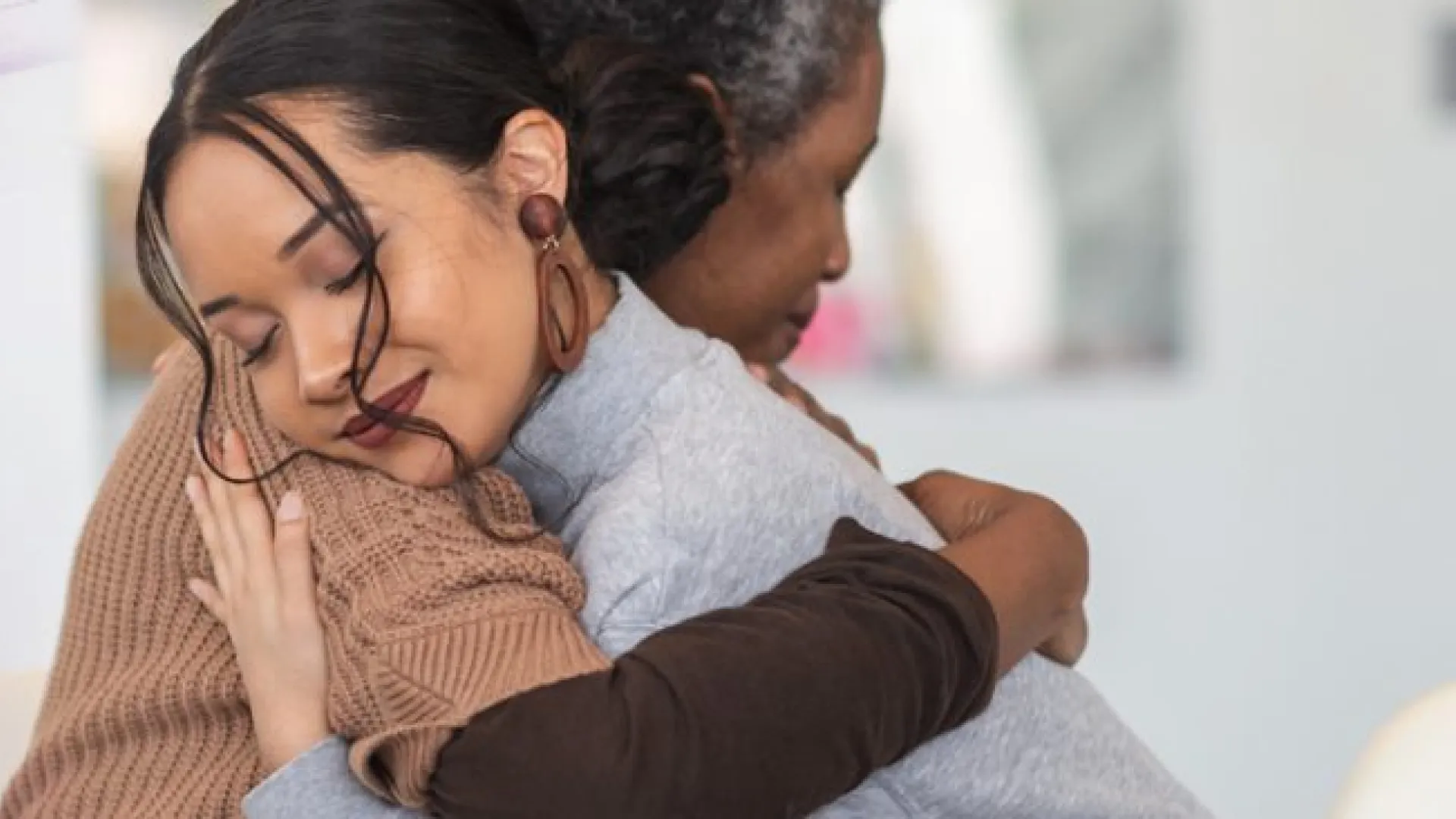 Two women embracing in a comforting hug beside text reading Grief Services on a purple gradient background.