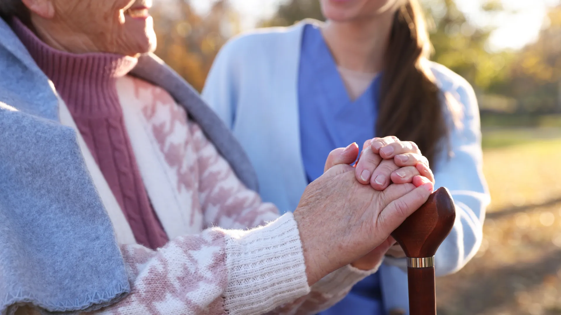 Senior volunteer reading a book and engaging in conversation with an elderly woman at home