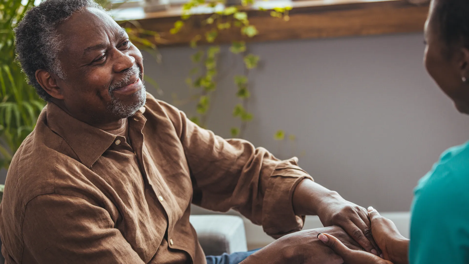 Senior man discussing dementia education with a younger woman in a comfortable setting with purple overlay.