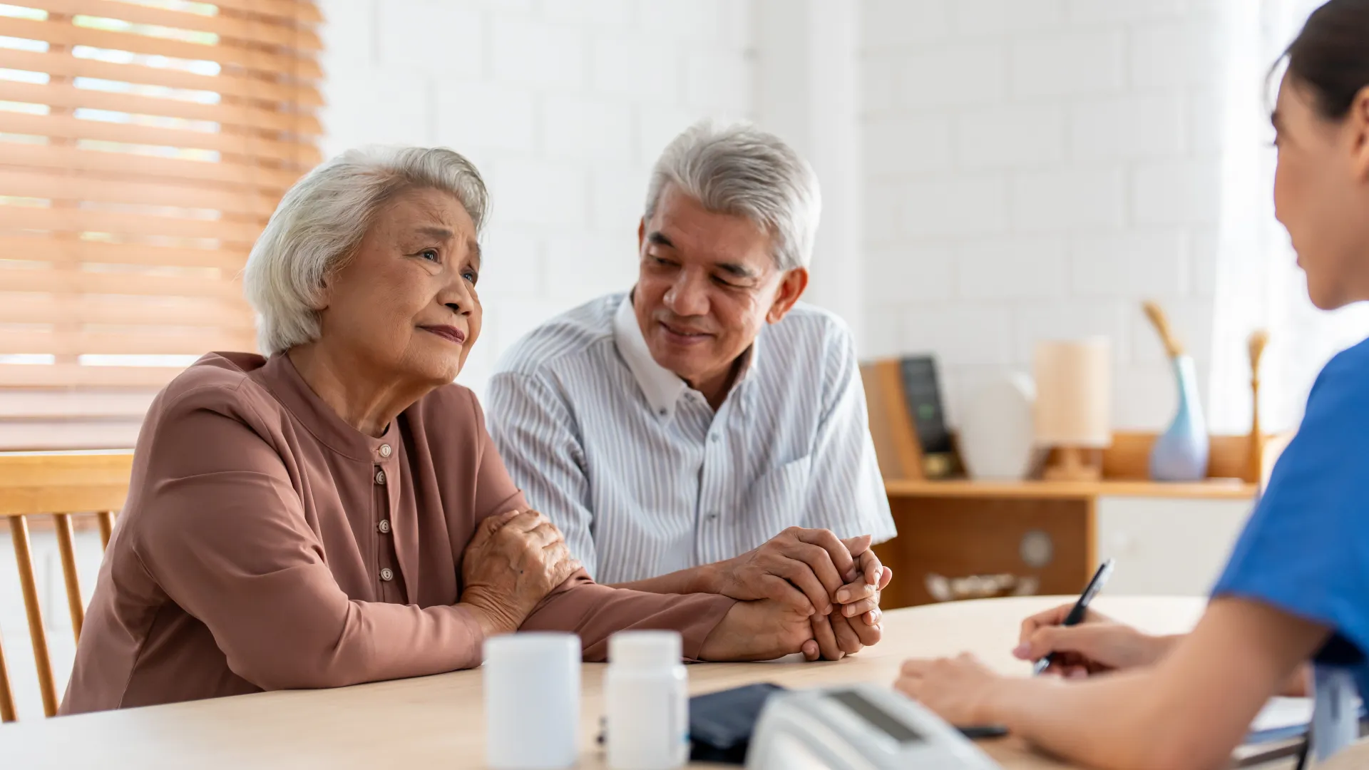 Senior couple consulting with a healthcare professional in a warm, bright clinic setting.