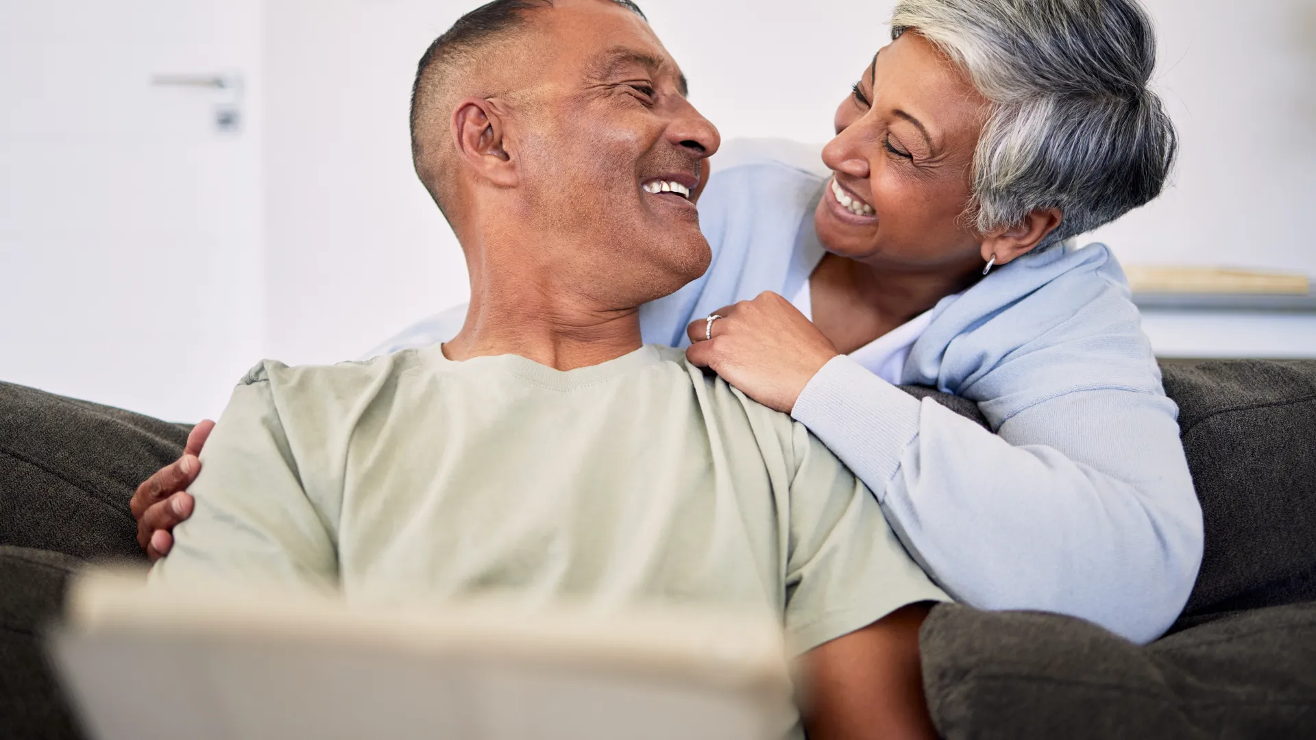 Happy couple enjoying time together on a cozy couch, sharing a joyful moment indoors.