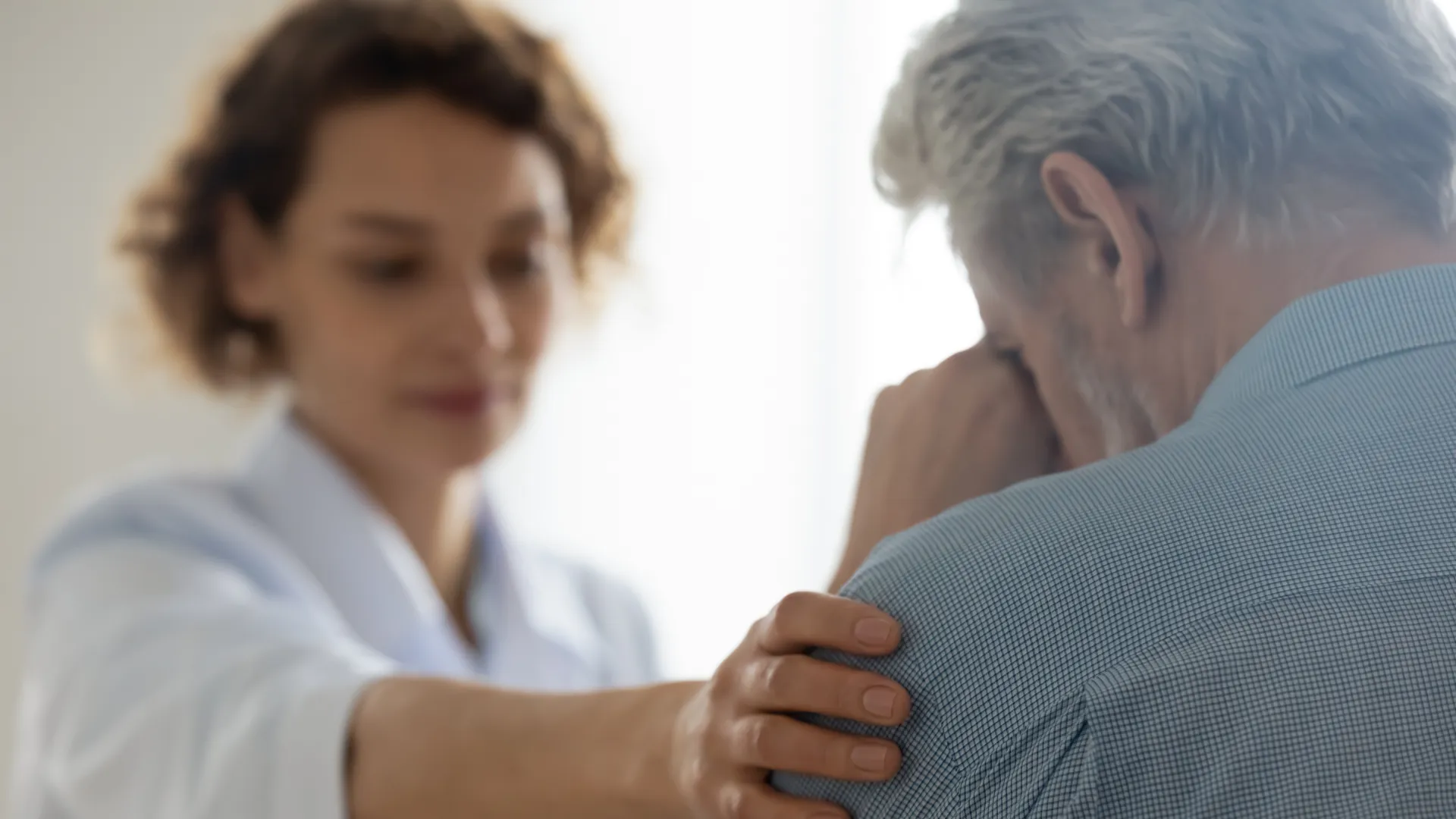 A therapist comforting an elderly man in a counseling session, showcasing empathy and support.