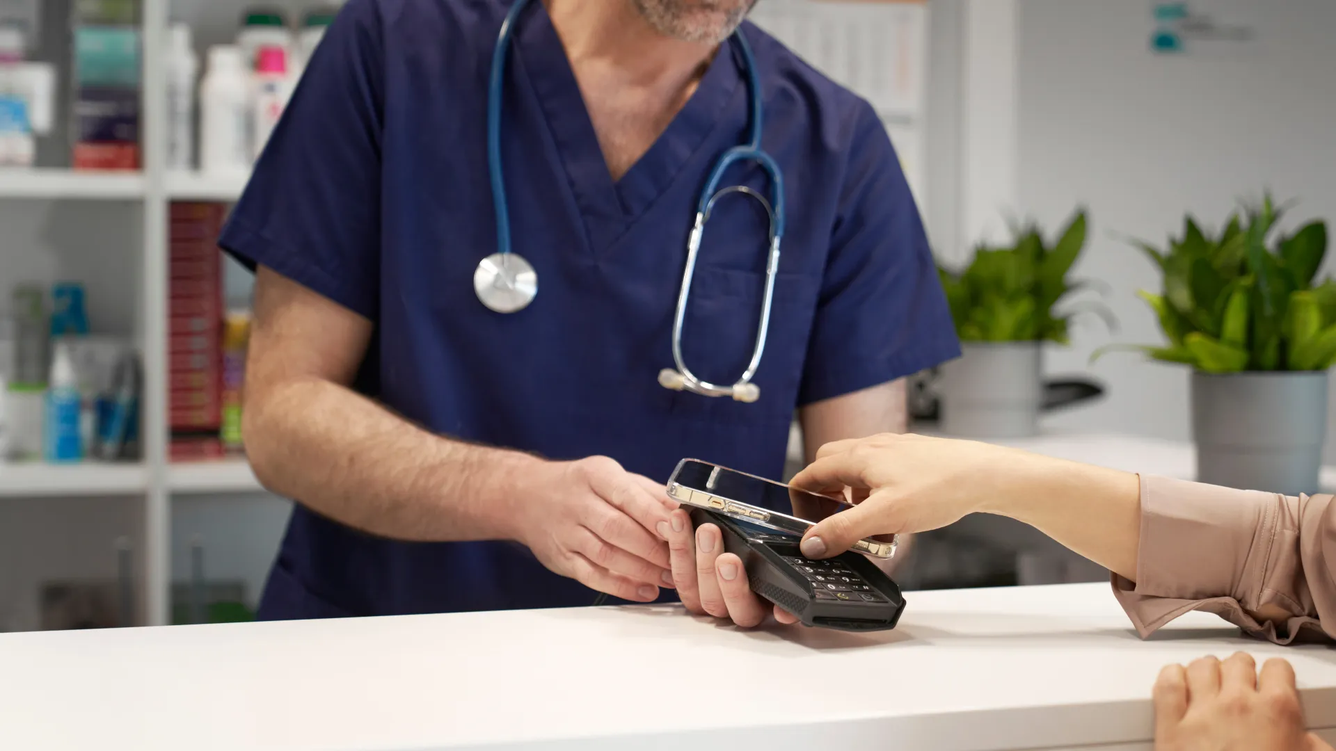A healthcare professional assists a patient with payment at a clinic's front desk.