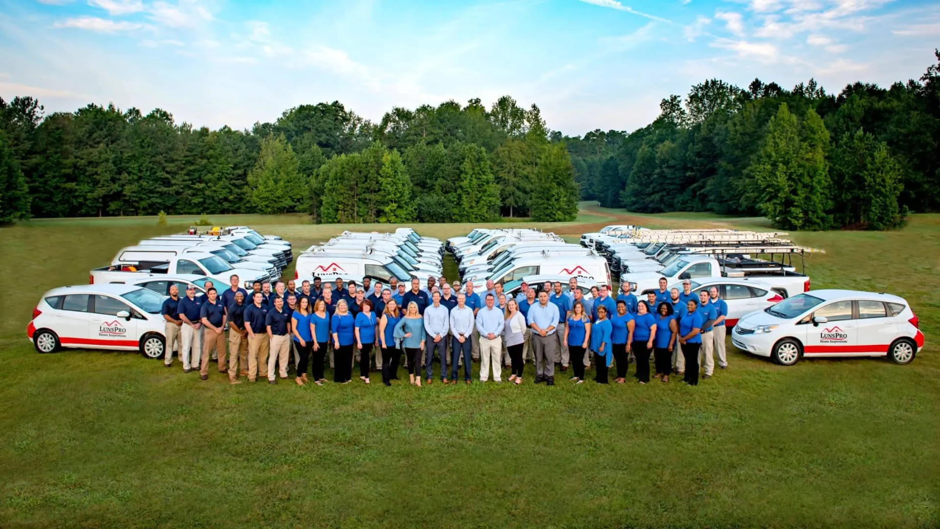 a group of people posing for a photo with cars and trees in the background