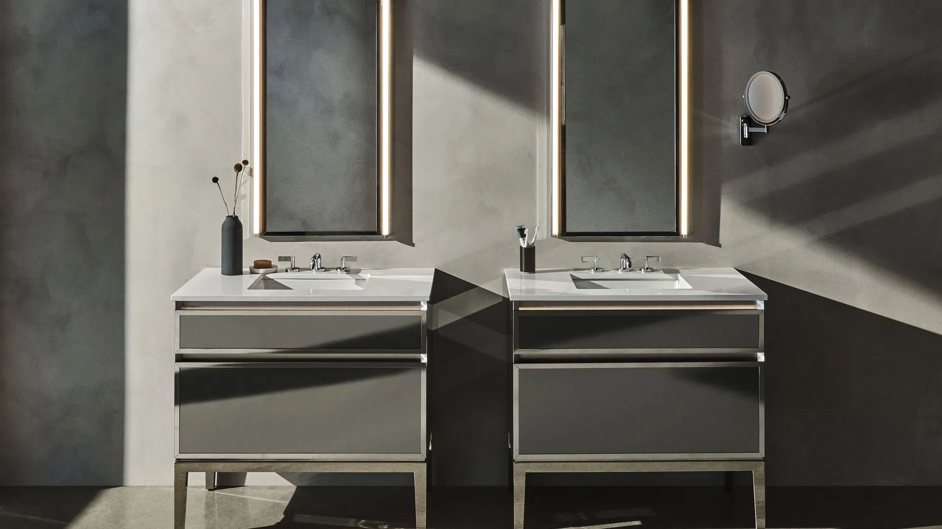 Modern double bathroom vanity with illuminated mirrors and minimalist decor against a concrete wall.