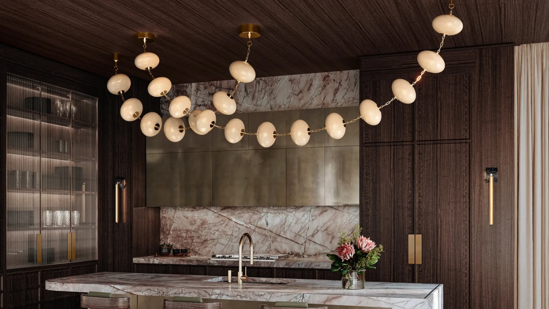 Modern kitchen with marble island, dark wood cabinetry, unique pendant lighting, and bar stools with green cushions.