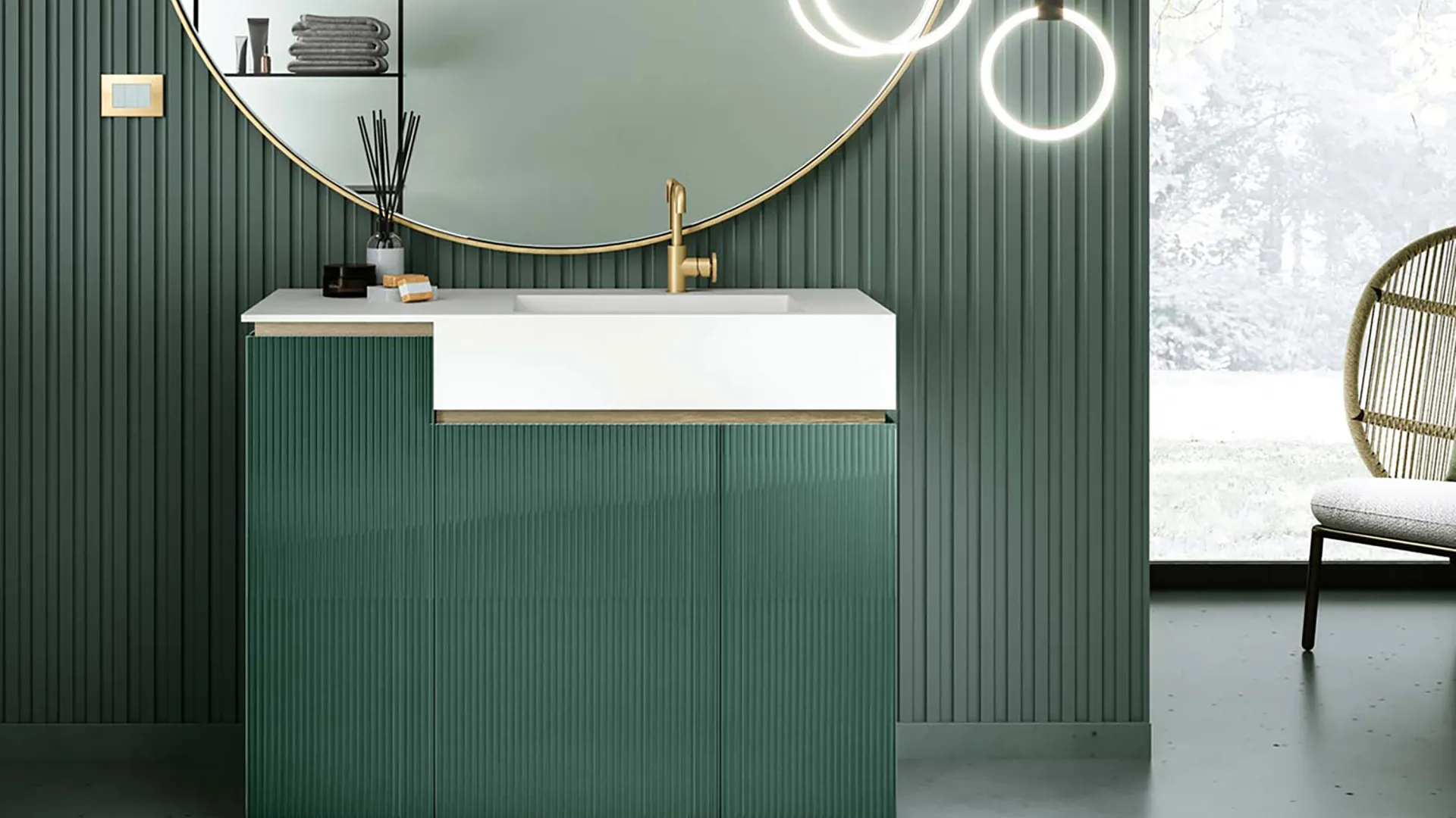 Modern bathroom with green vertically grooved walls, round mirror with gold trim, white sink, and pendant lights.