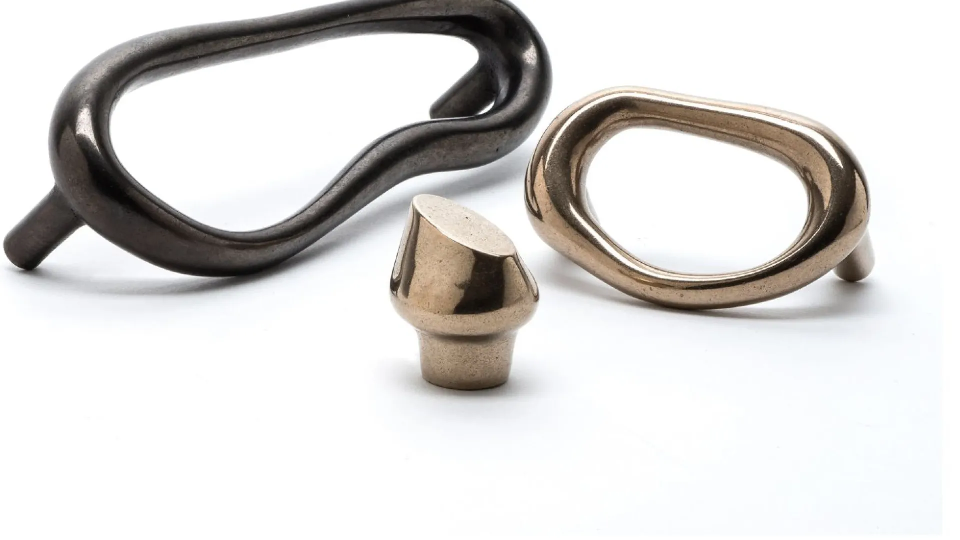 Three stylish metal hardware pieces in bronze and black finishes showcased on a white surface, winner of 2022 Luxe RED Awards.