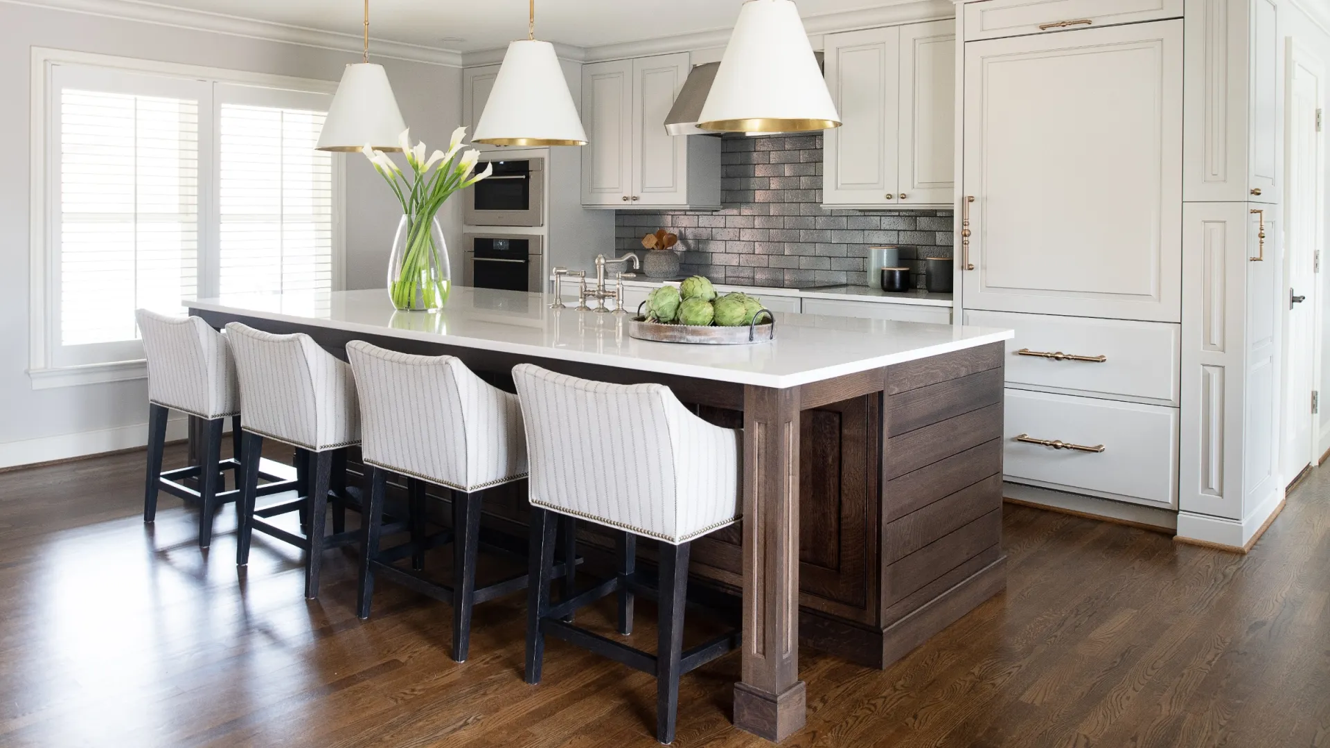 Modern kitchen featuring an island, white cabinetry, stylish lighting, and elegant decor elements.