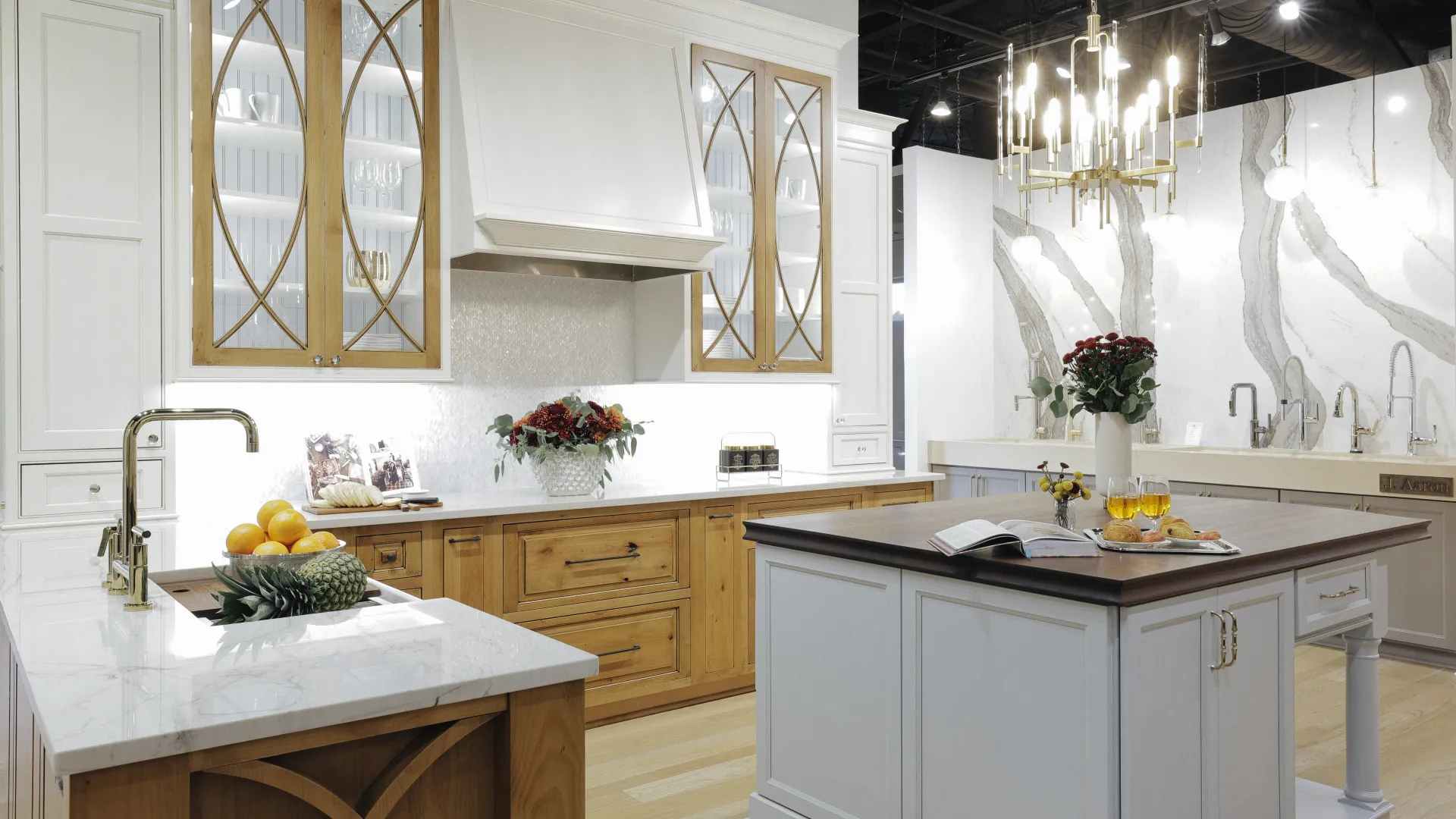 Modern kitchen with white and wood cabinetry, marble countertops, central island, and decorative lighting fixtures.